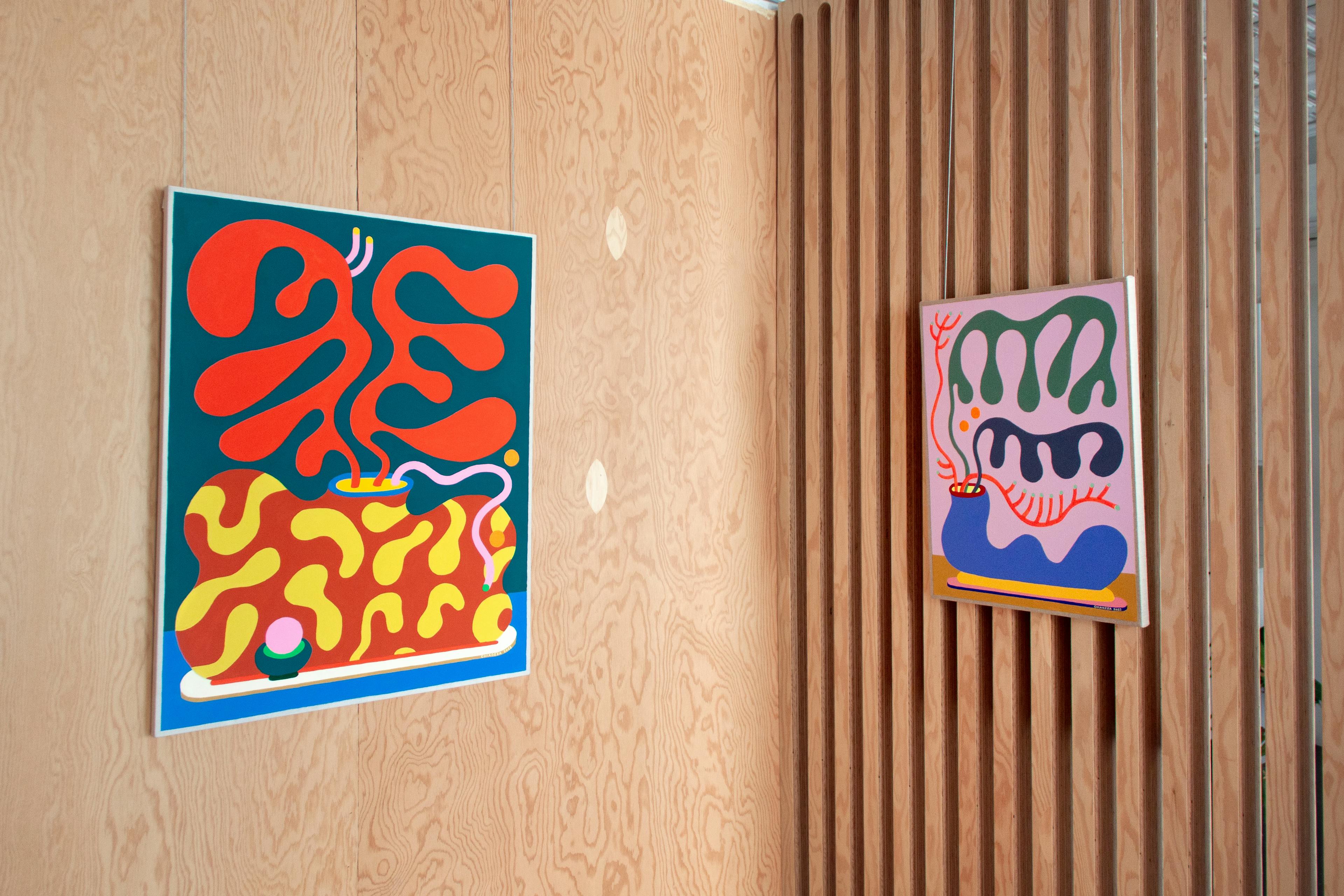 Colorful abstract paintings by Adam Frezza and Terri Chiao, known as CHIAOZZA, hang in a gallery for the exhibition Slow Growth.