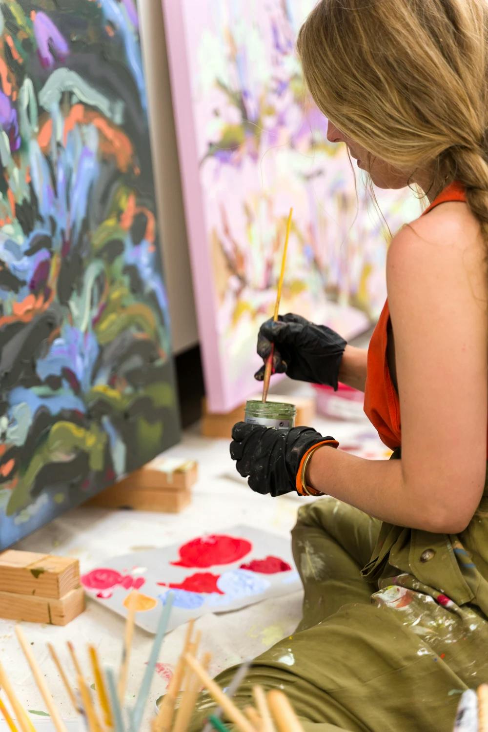 Artist Erin Lynn Welsh working on two large floral paintings in her studio. 