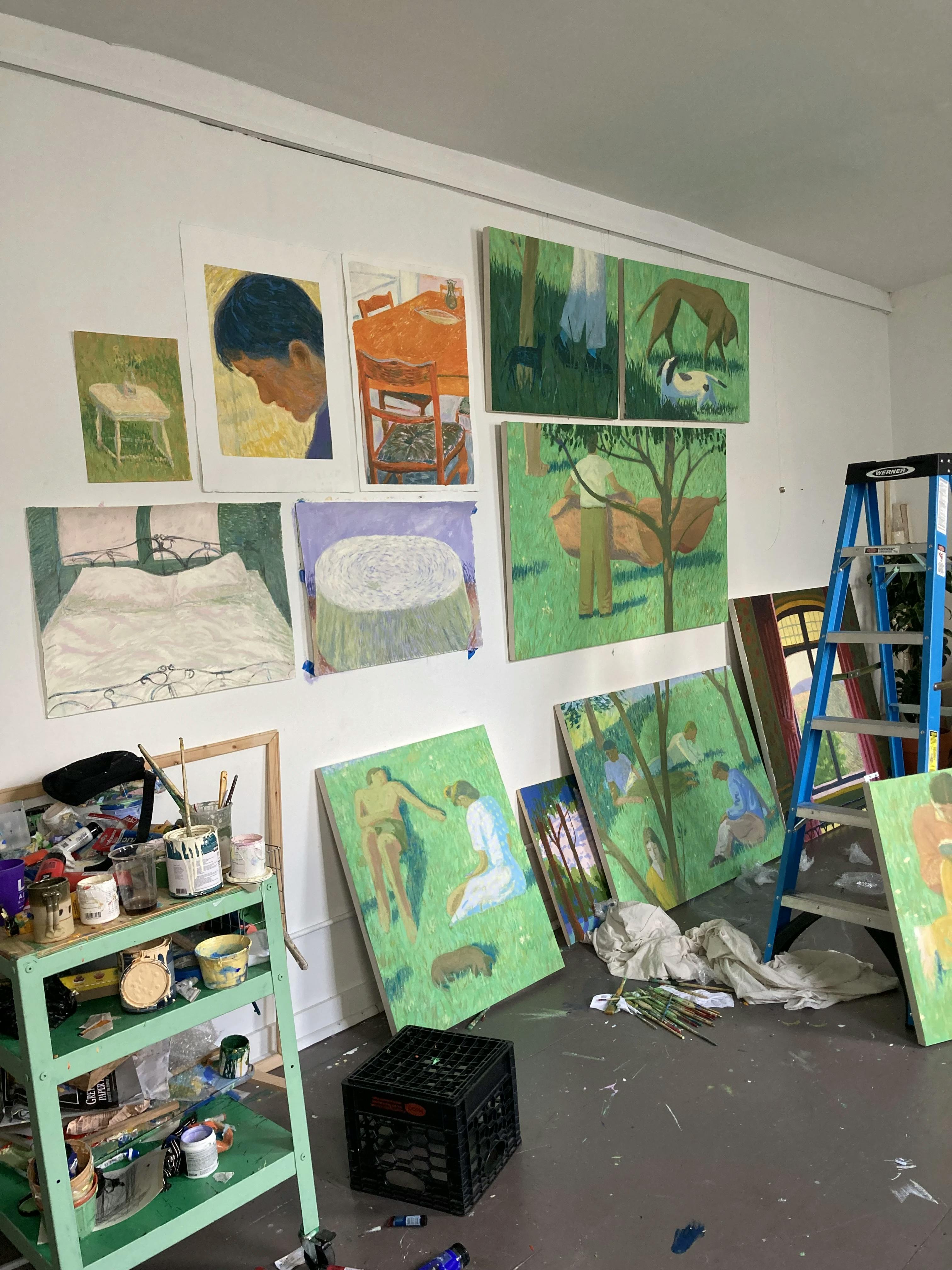 Brightly colored paintings of various sizes installed on a white wall in artist Jackson Joyce's studio.