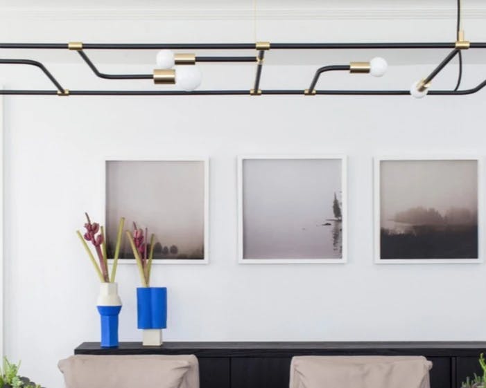 Three framed photographs by artist Anna Moller installed on a white wall in a dining room.