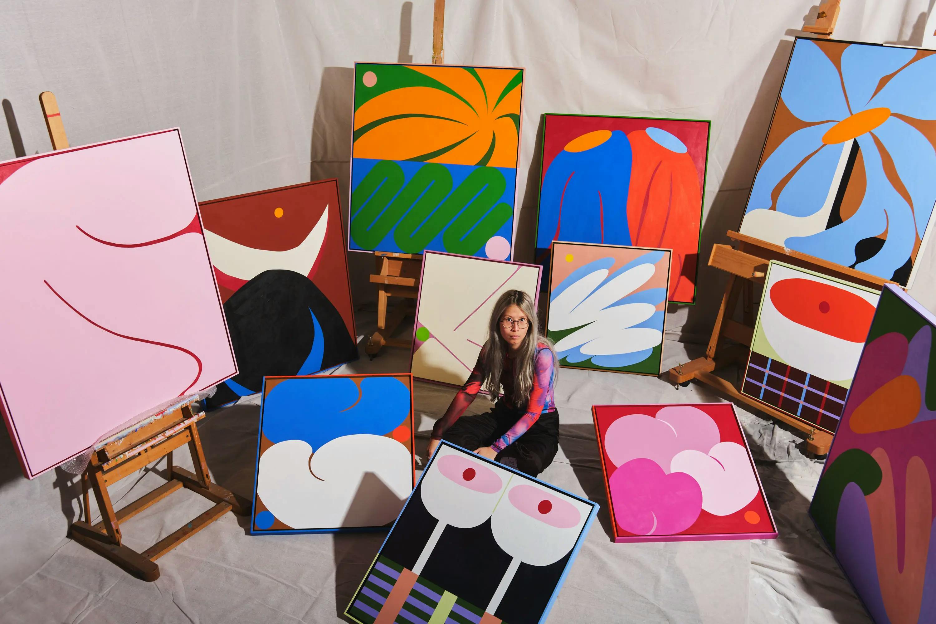 The artist Evi O. surrounded by twelve of her large colorful abstract paintings. 