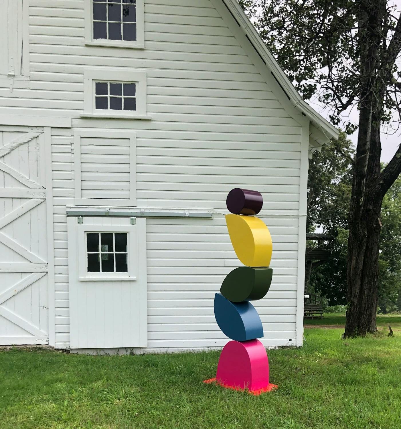 Oversized, aluminum sculpture by artist Vicki Sher outside in a grassy field next to a white barn.