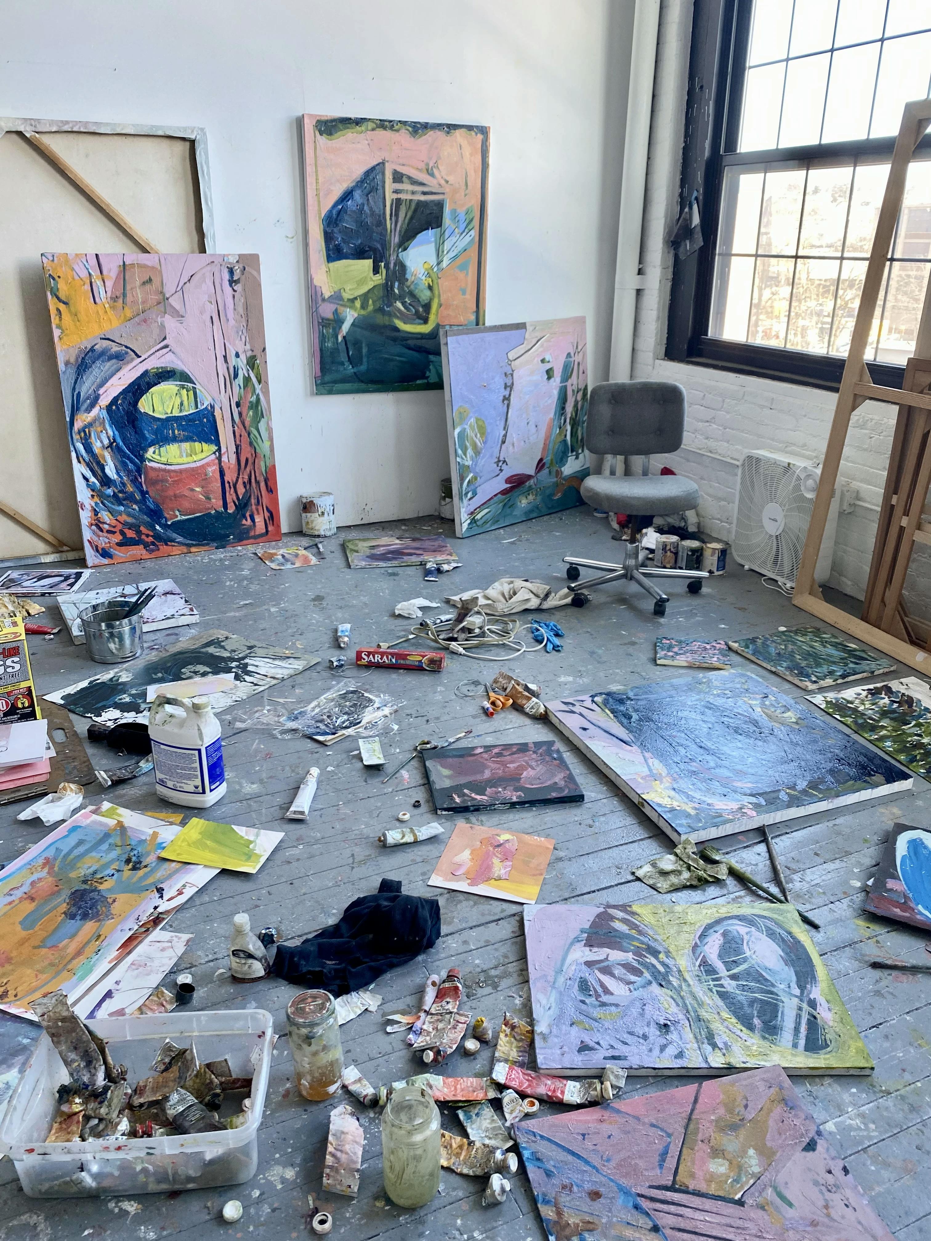 Abstract paintings of various sizes on the floor and installed on the wall in artist Diana Delgado's studio/
