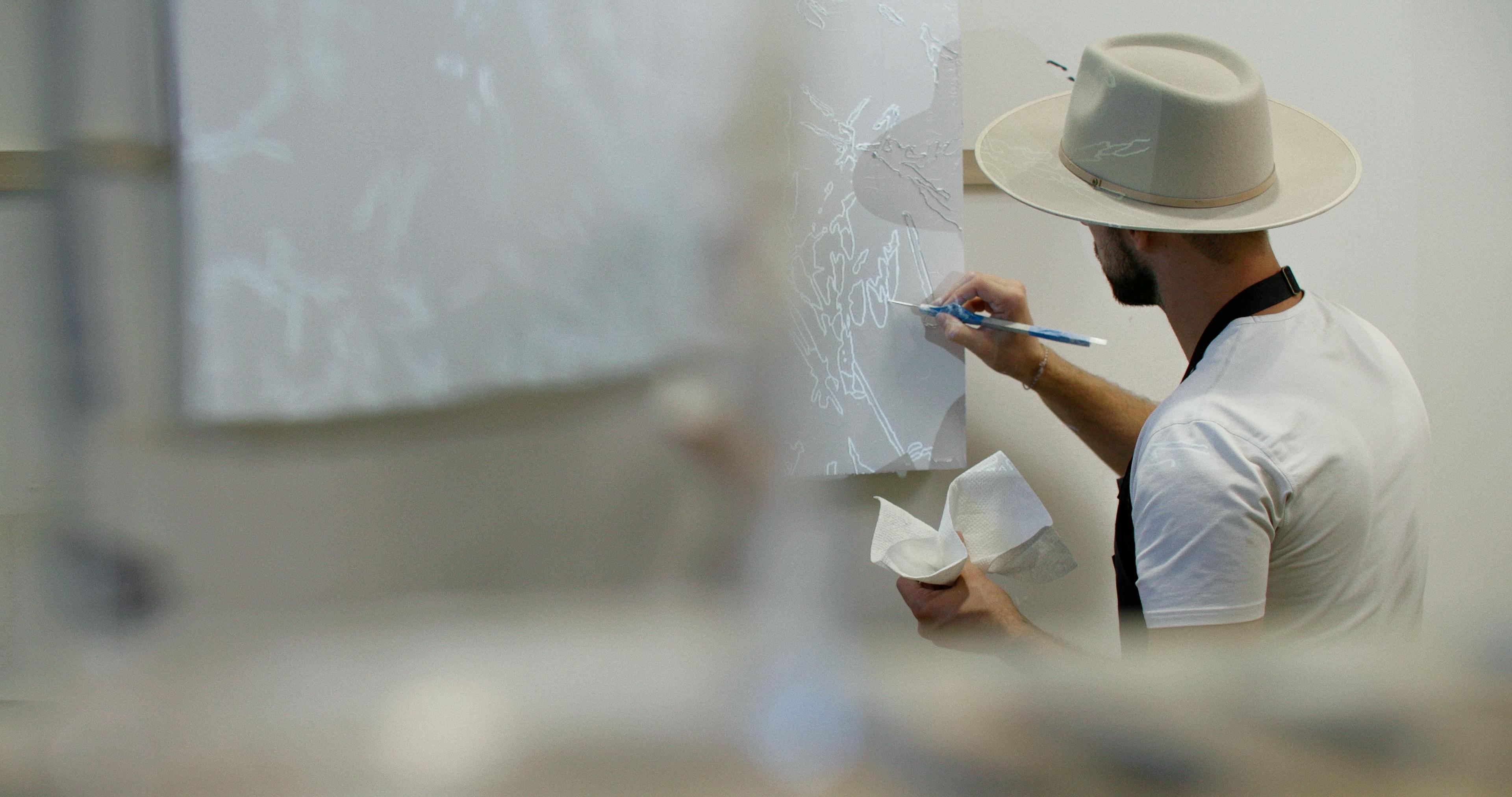 Artist Blake Aaseby painting a white canvas in his studio.