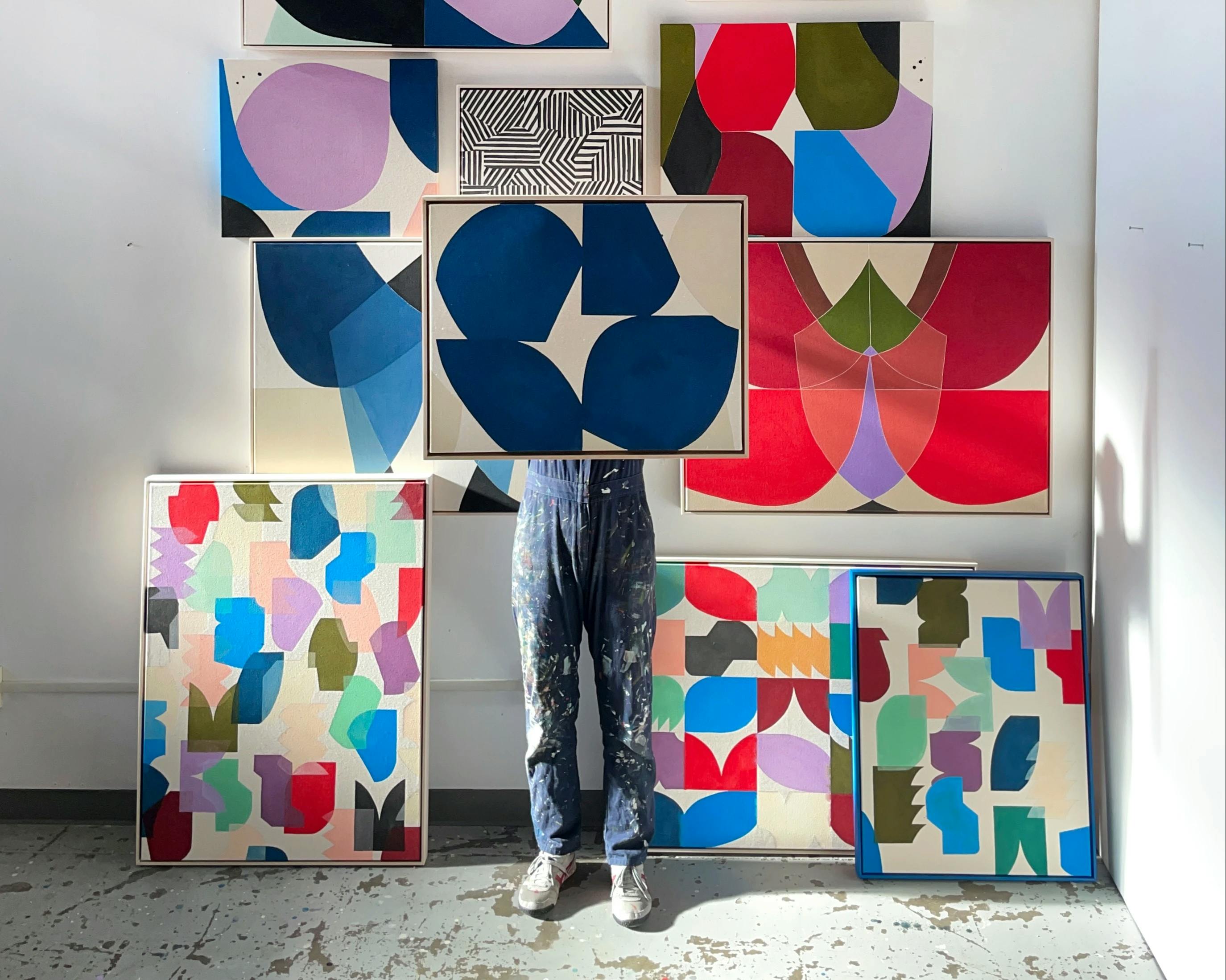 Artist Christina Flowers holding up abstract, geometric works in her studio.