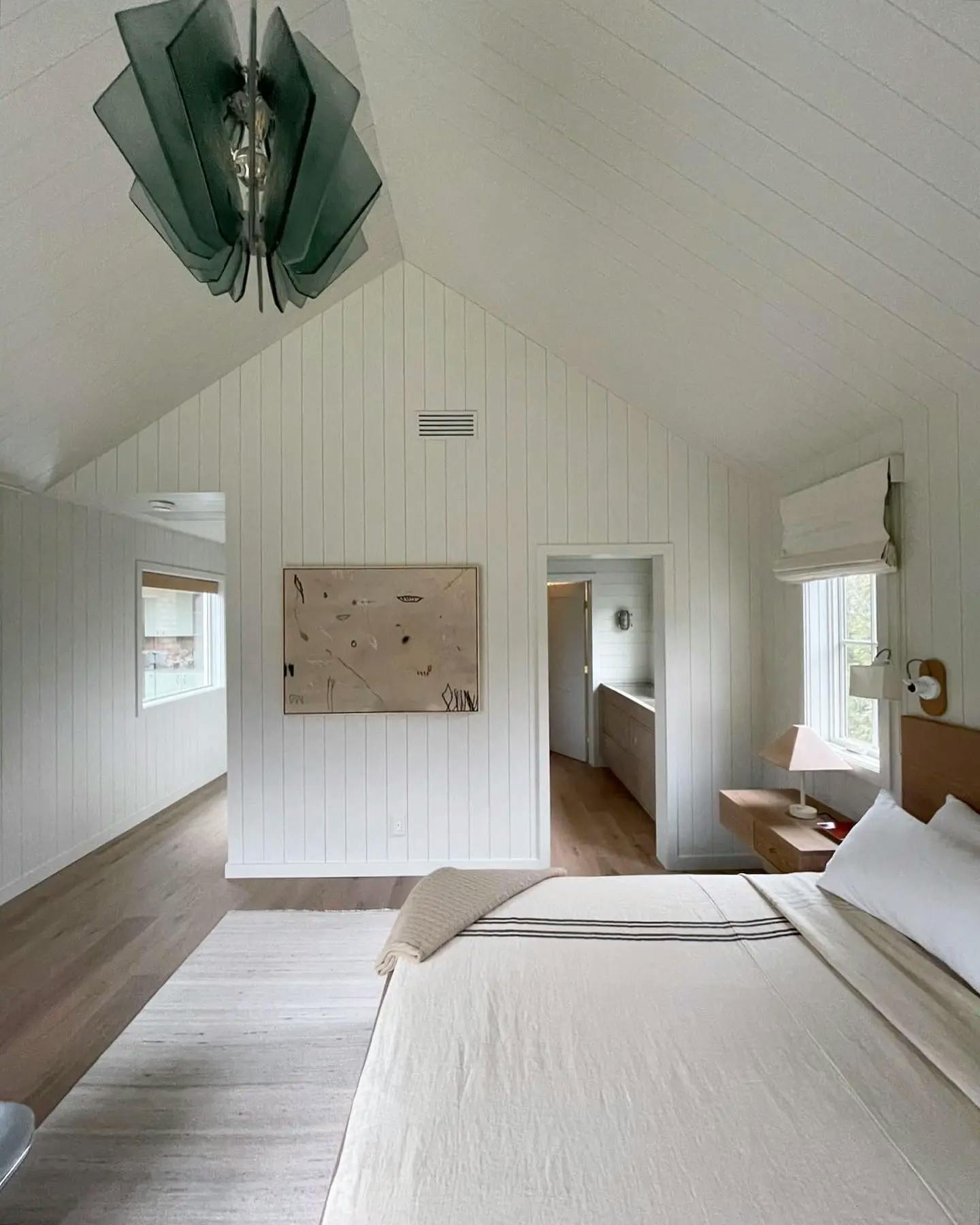 A distressed painting by artist Saxon Quinn in a neutral bedroom with vaulted ceilings.