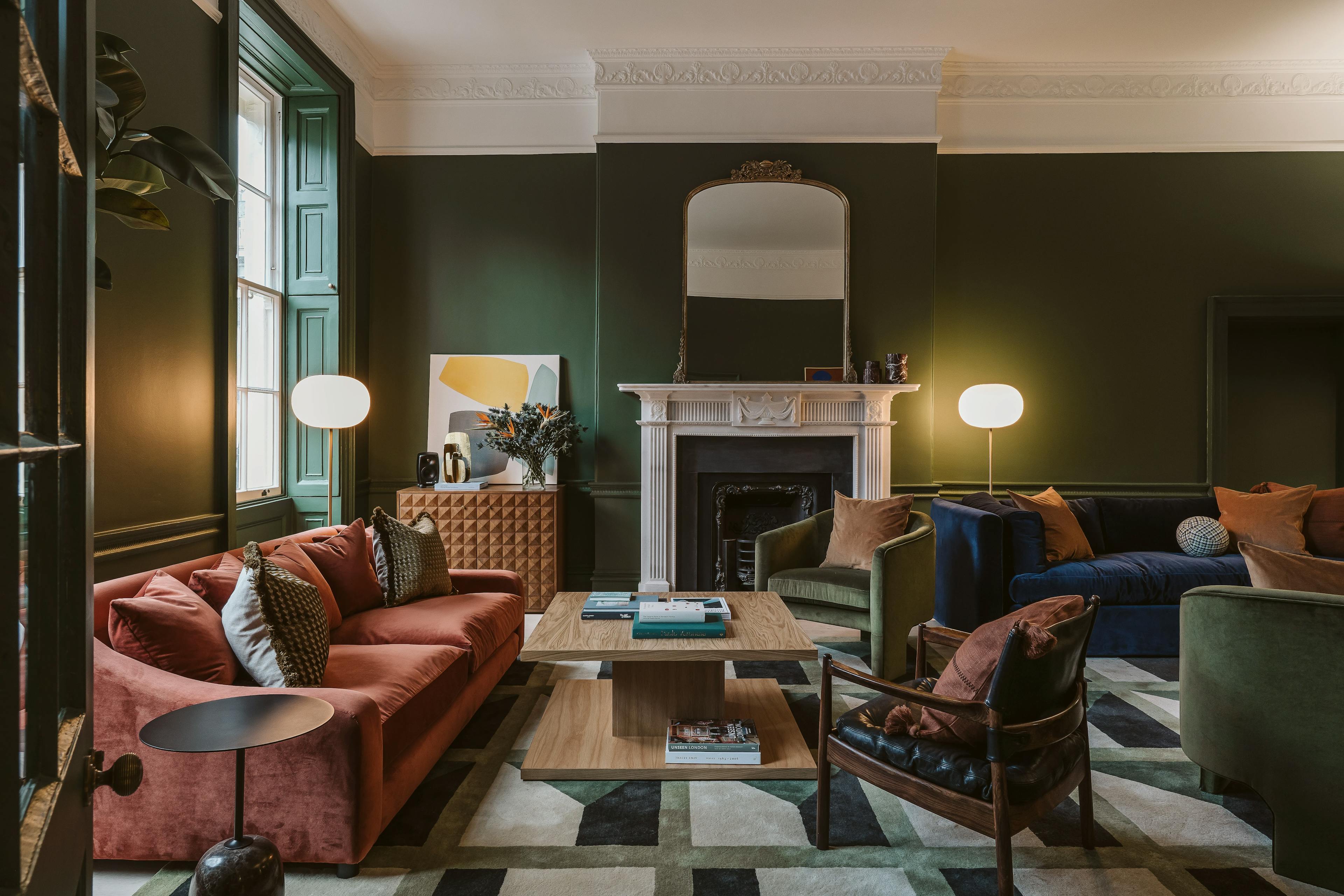 An abstract painting by artist Mia Farrington on top of a brown cabinet, leaning against a dark green wall within a lounge area at the Chief London clubhouse.