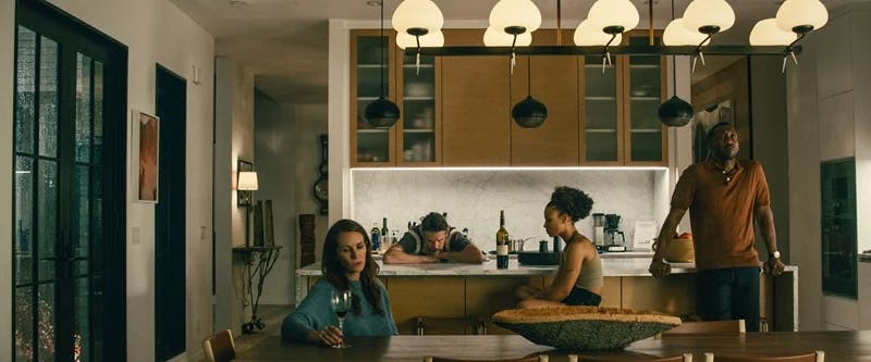 A red painting by artist Misato Suzuki in a film still of a modern kitchen from the Netflix movie, Leave the World Behind, featuring actors Julia Roberts, Myha'la Jael Herrold, and Mahershala Ali.