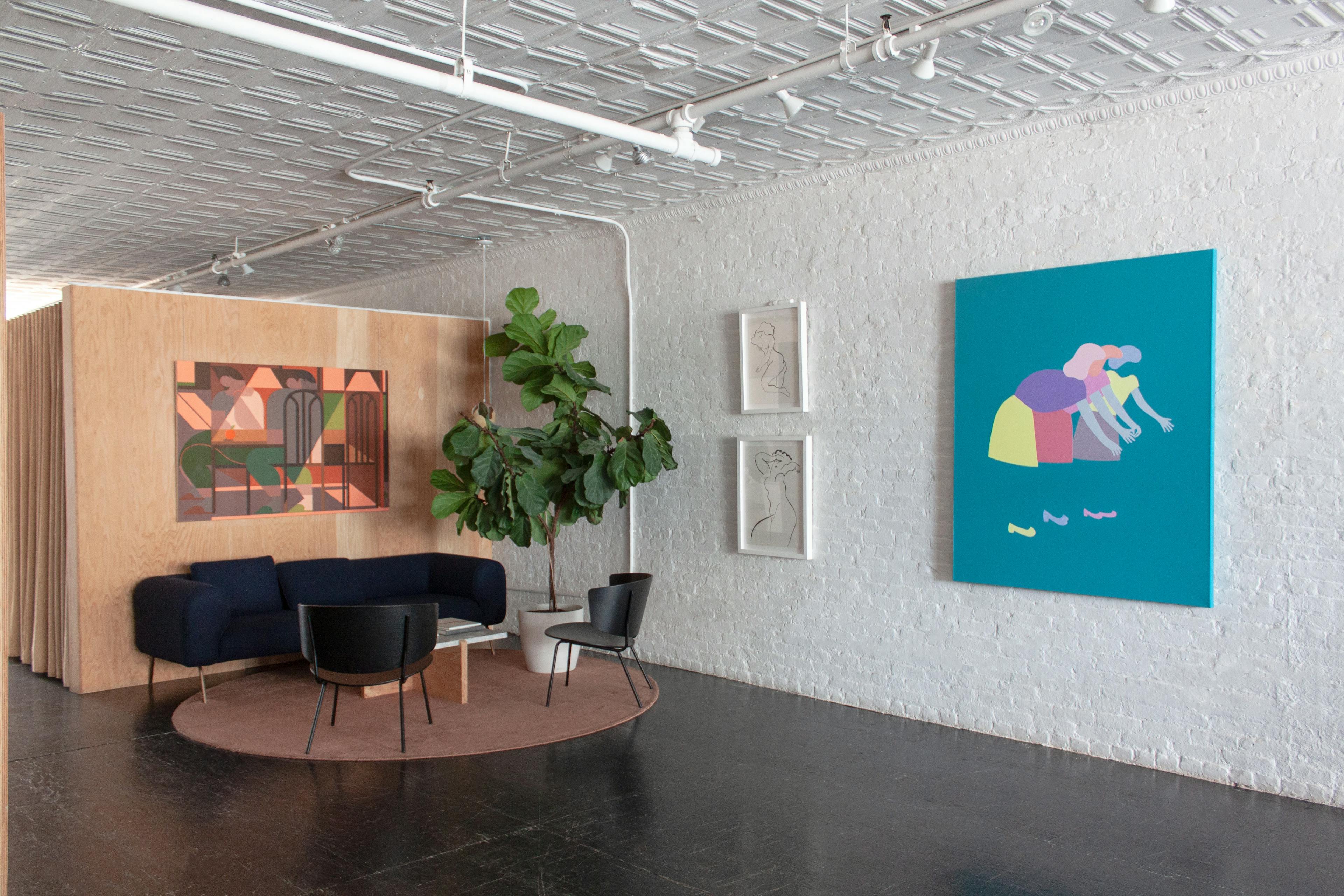 A teal painting of characters reaching by artist Dana Bell next to artwork by artists Ousmane Ba and Adrian Kay Wong above a blue sofa at Uprise Art for the Figurative collection.
