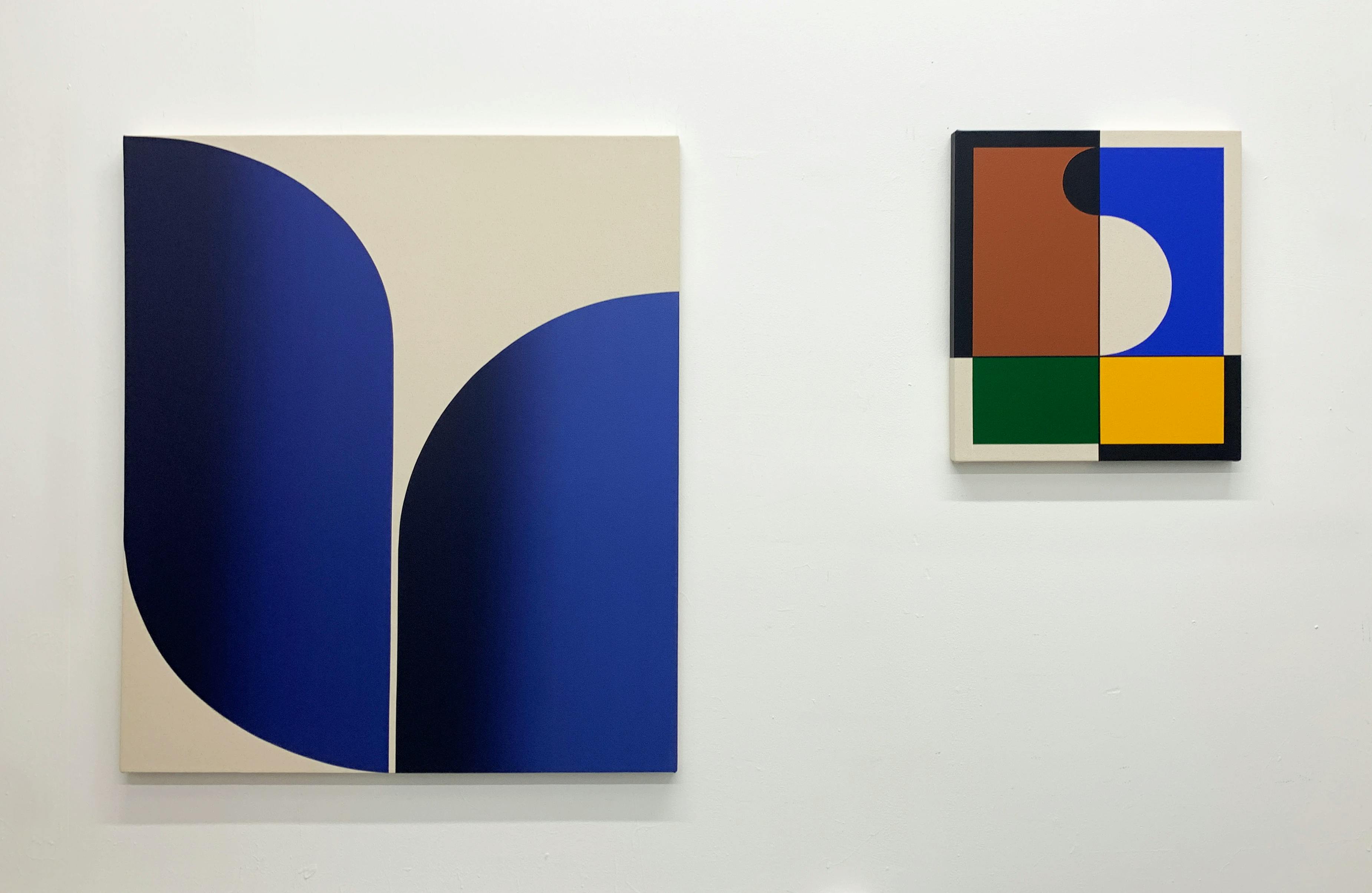 Two paintings, a minimalist blue painting and a small abstract one with geometric shapes, by artist Senem Oezdogan.