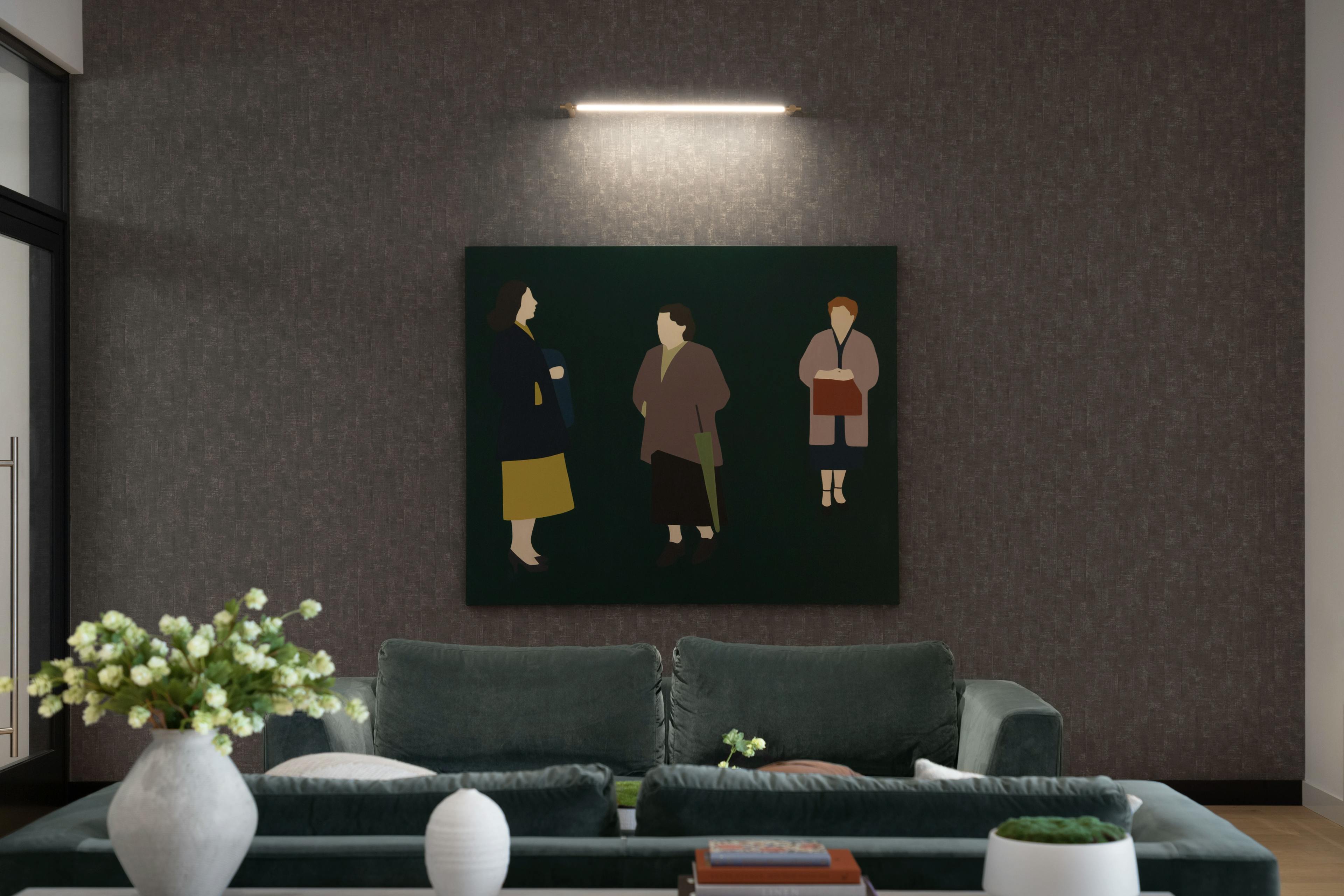 A large figurative painting of three women in overcoats by artist Dana Bell installed over a gray sofa in Gotham Point.