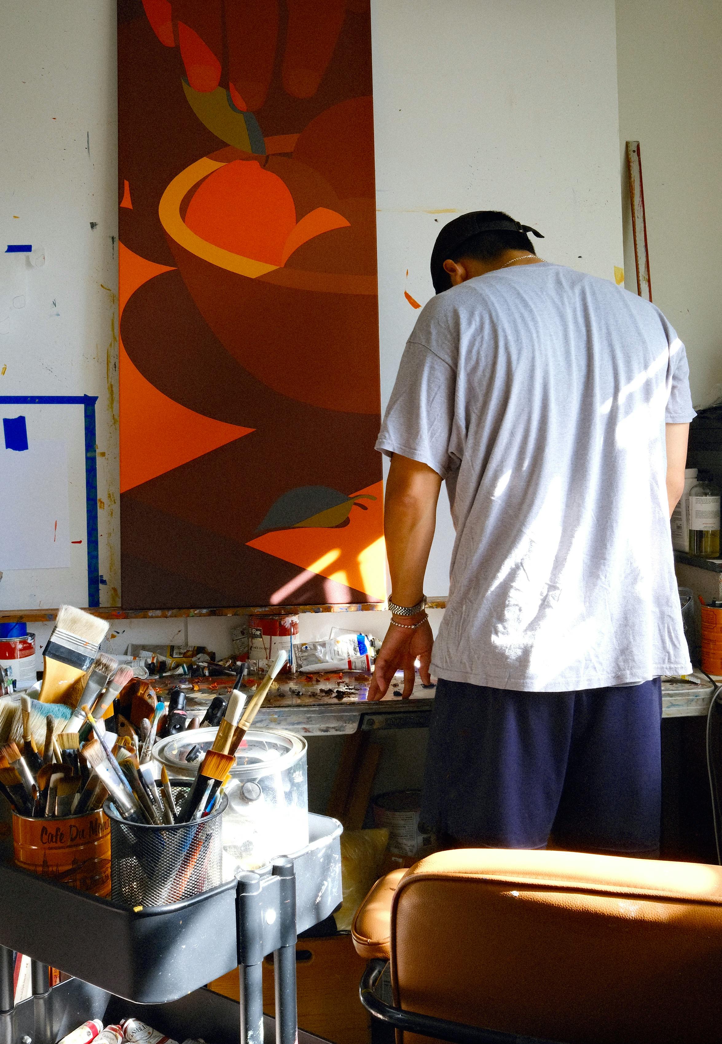 Artist Adrian Kay Wong standing in front of a painting in his studio. 