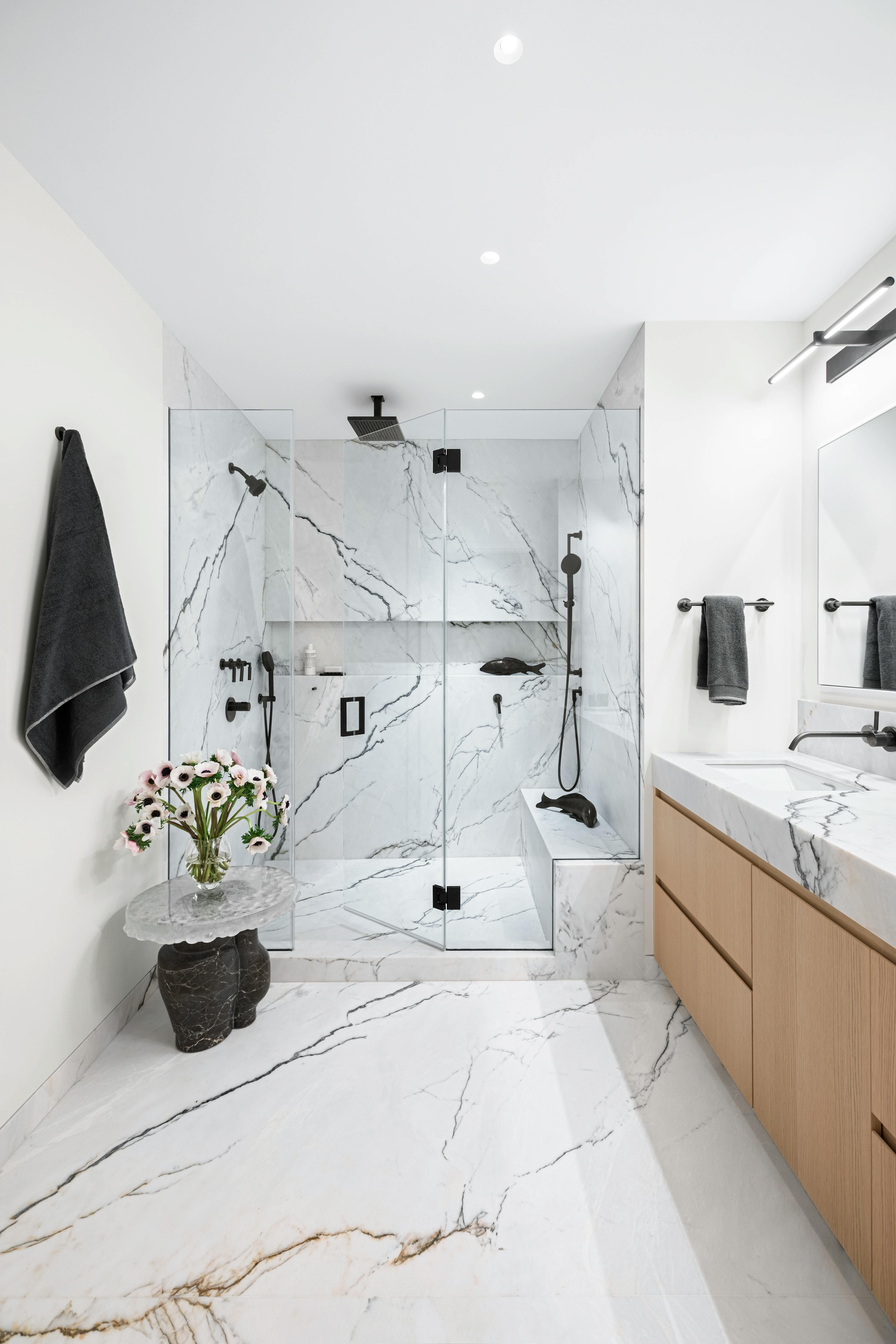 Modern black and white bathroom with a large glass shower and marbled tile.