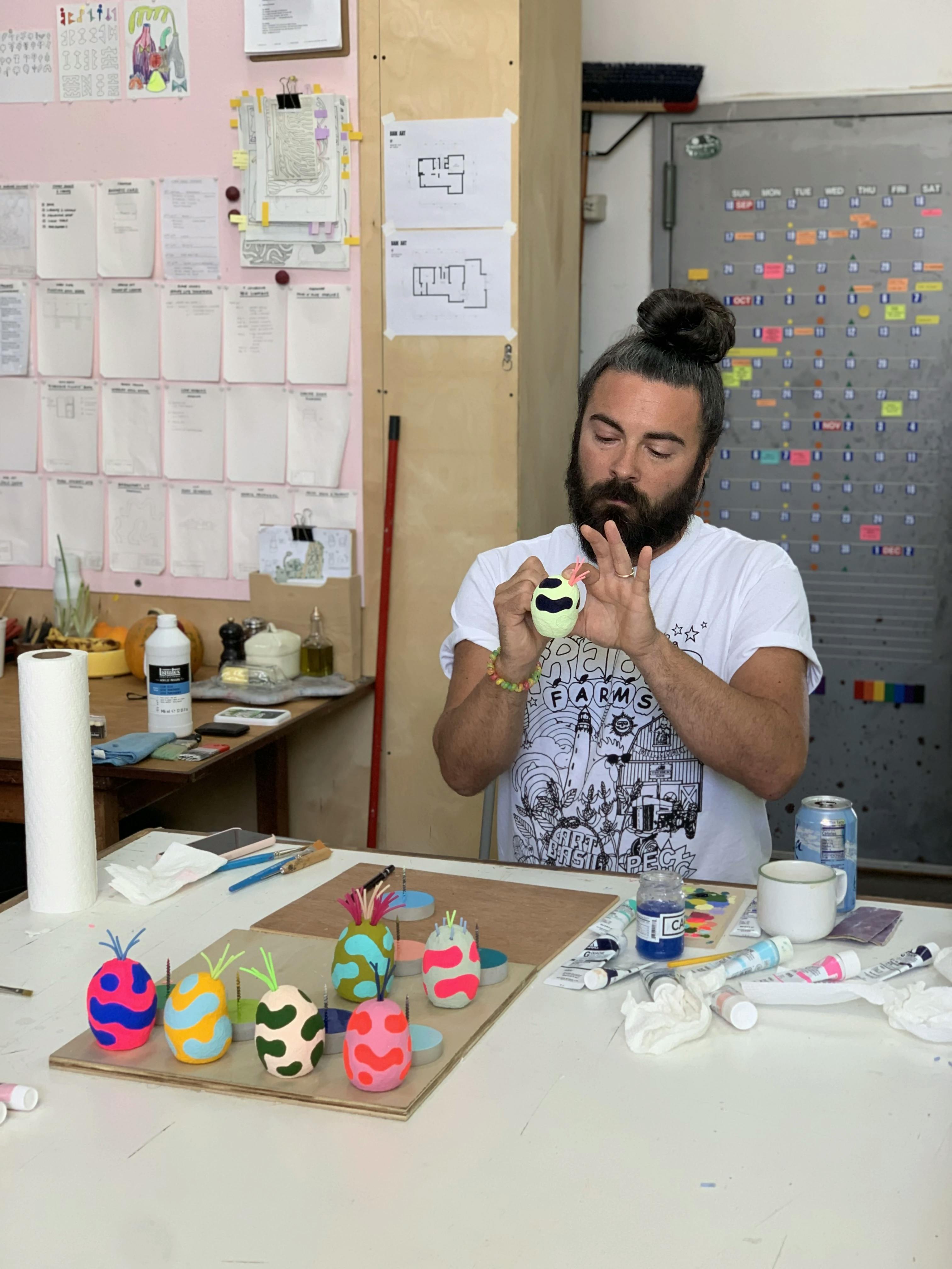 Adam Frezza of the artist duo CHIAOZZA painting Lump Nubbins, small whimsical sculptures, in his studio.