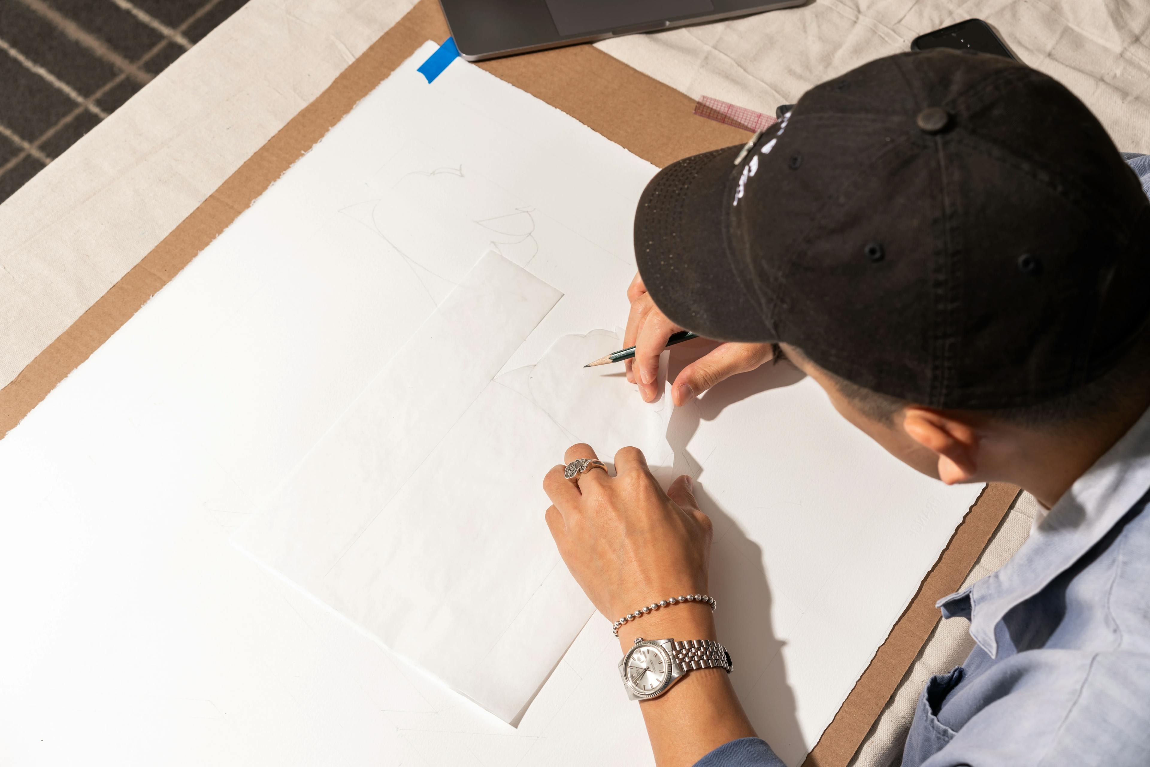 An overhead look as Adrian Kay Wong uses a piece of vellum to sketch out an artwork inspired by MacArthur Place.