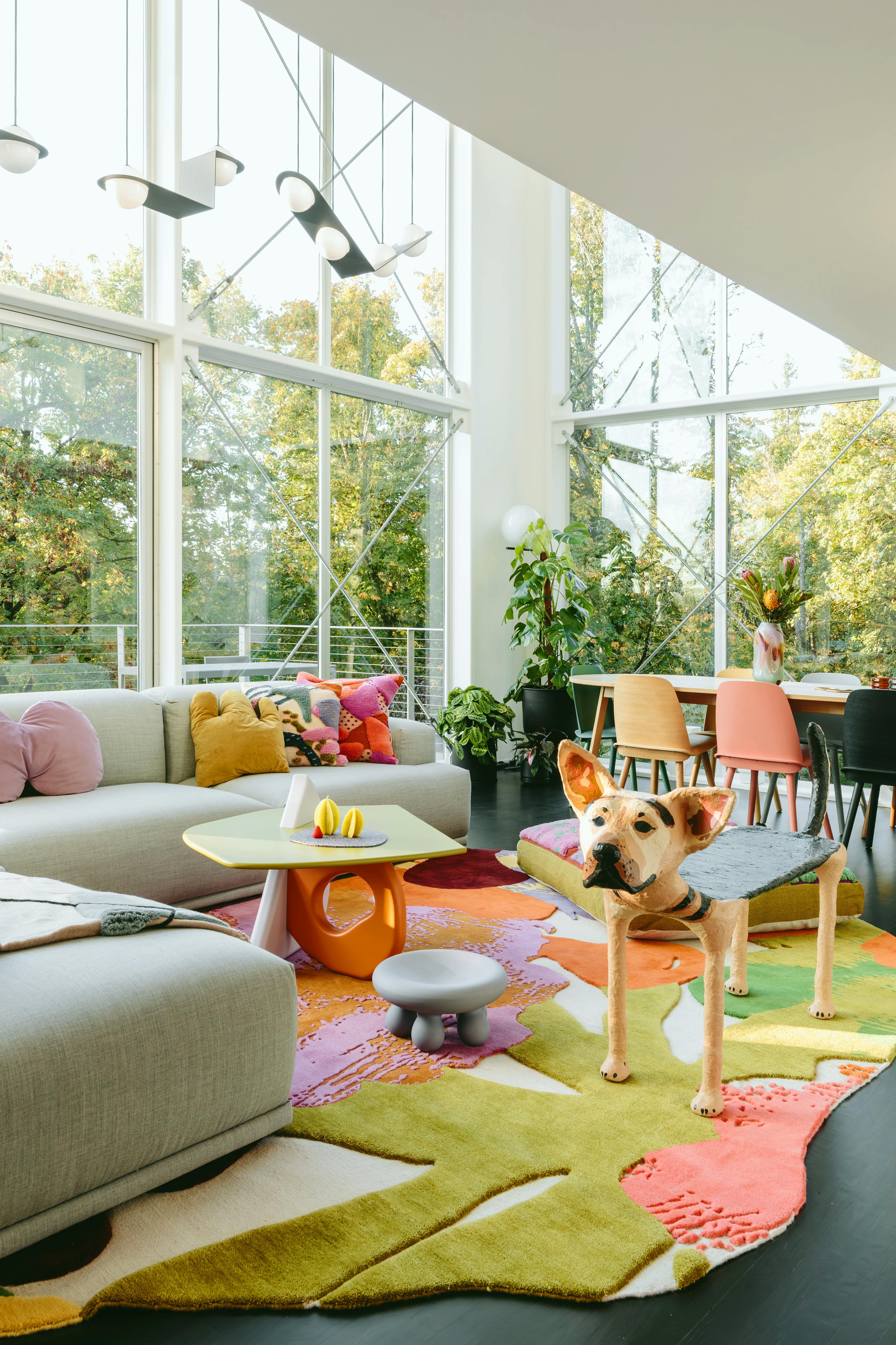 Modern living with floor-to-ceiling windows, complete with a gray sectional and colorful pattern rug.