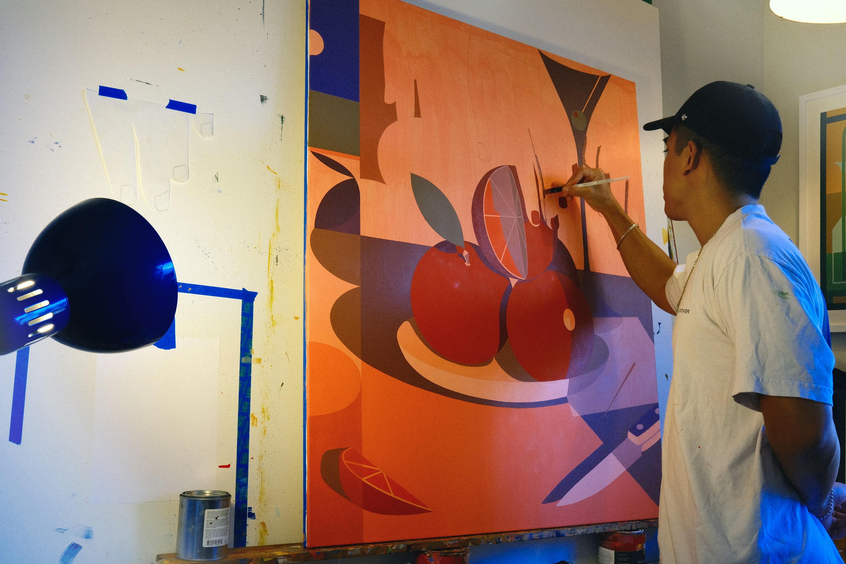 Artist Adrian Kay Wong, working on a large orange painting in his studio. 