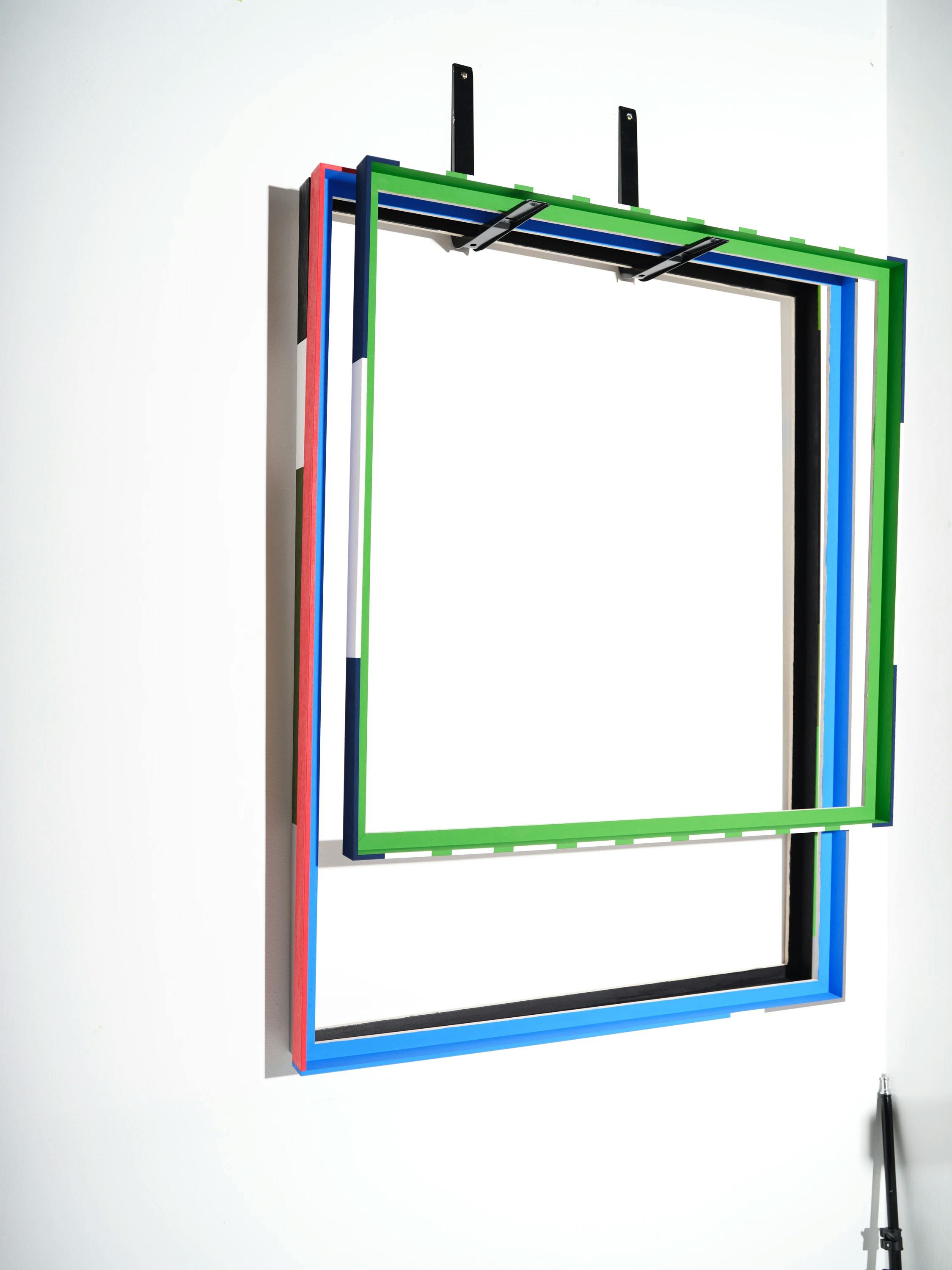 Two colorfully painted floater frames hanging in Evi O's studio.