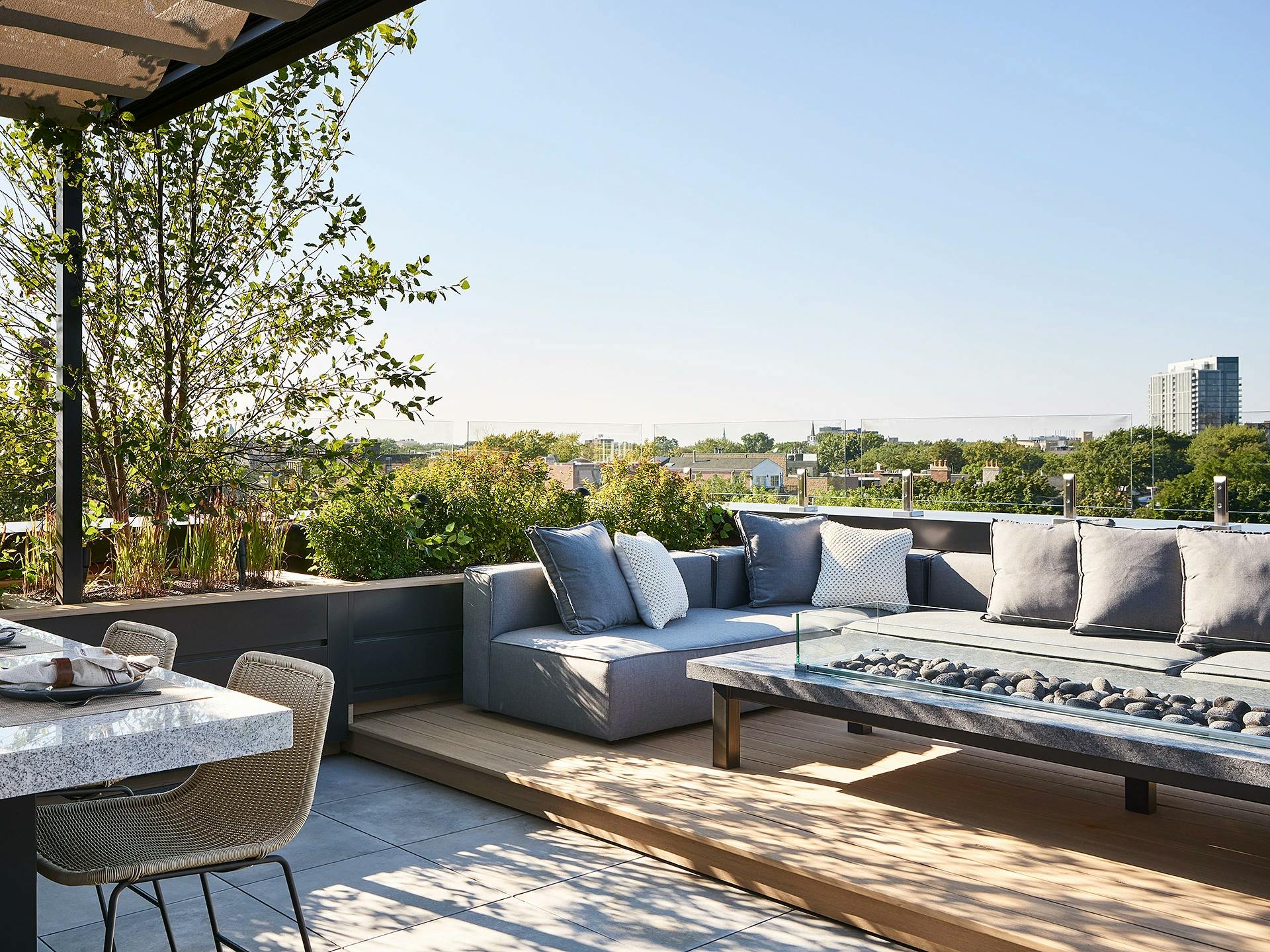Roof deck lounge area with a gray sectional sofa overlooking a Chicago skyline.