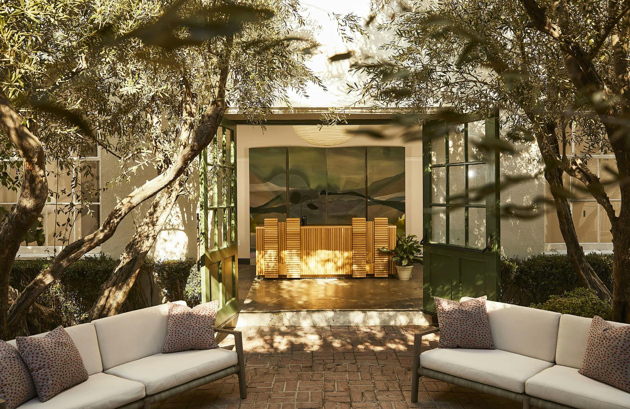Green french doors leading to the outside patio with trees at the Chief Los Angeles Clubhouse.