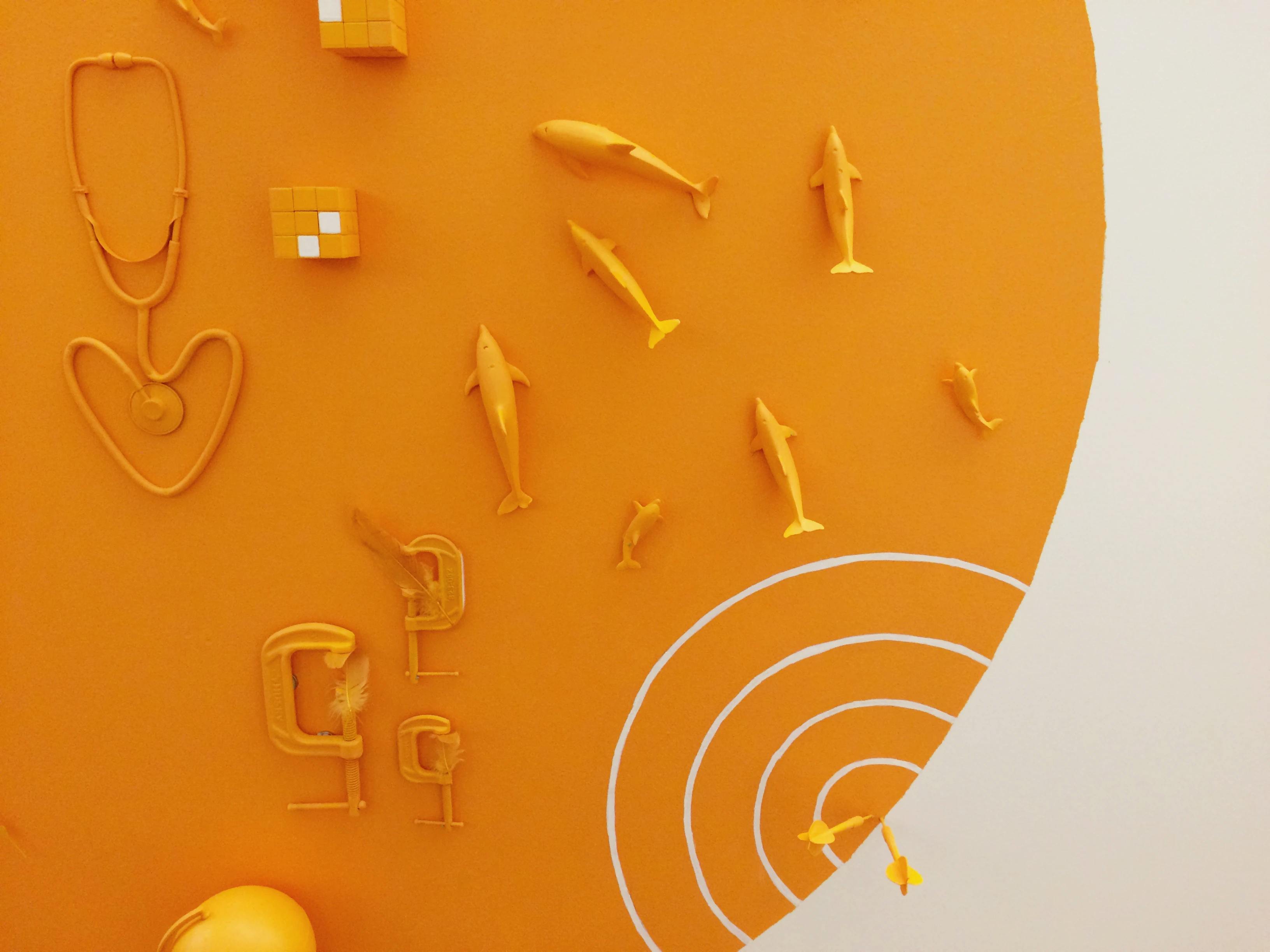 Close-up of an orange wall installation with sharks and a stethoscope by artist Christina Watka.