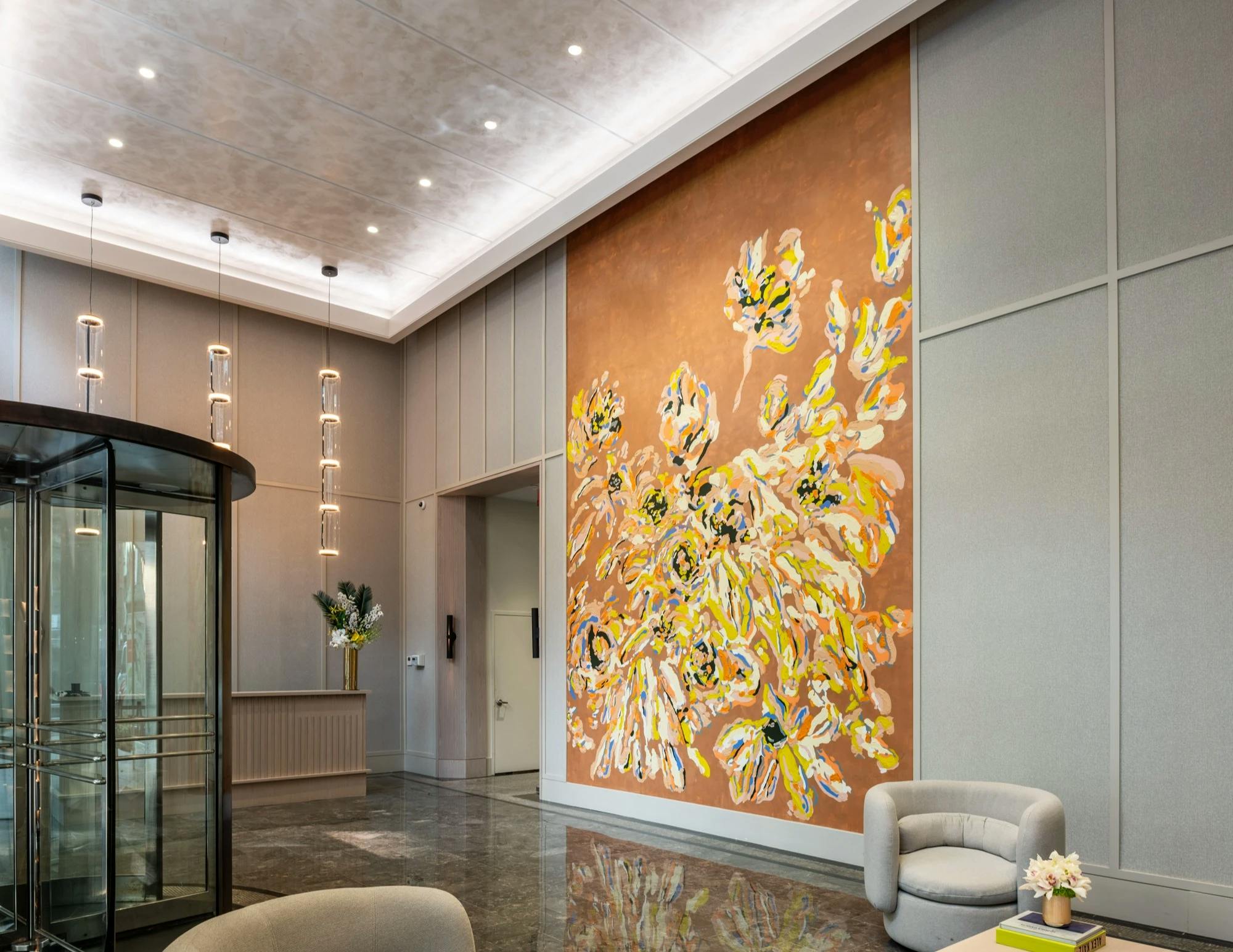 A large brown, yellow, and white floral mural by artist Erin Lynn Welsh flanked by two leather chairs in the lobby of Anagram NoMad.