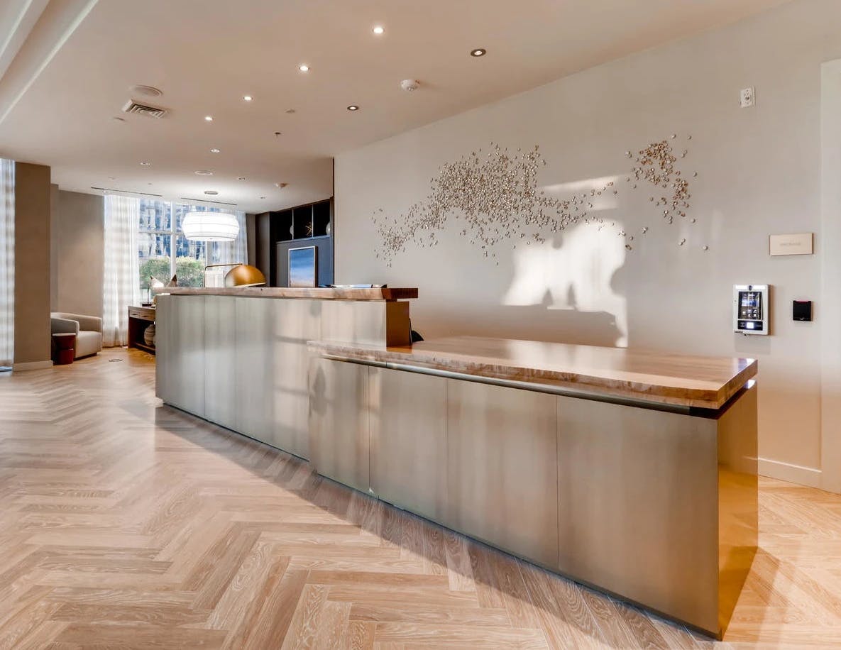 A porcelain Murmuration sculpture by artist Christina Watka installed above a stone reception desk at Liberty Harbor East.