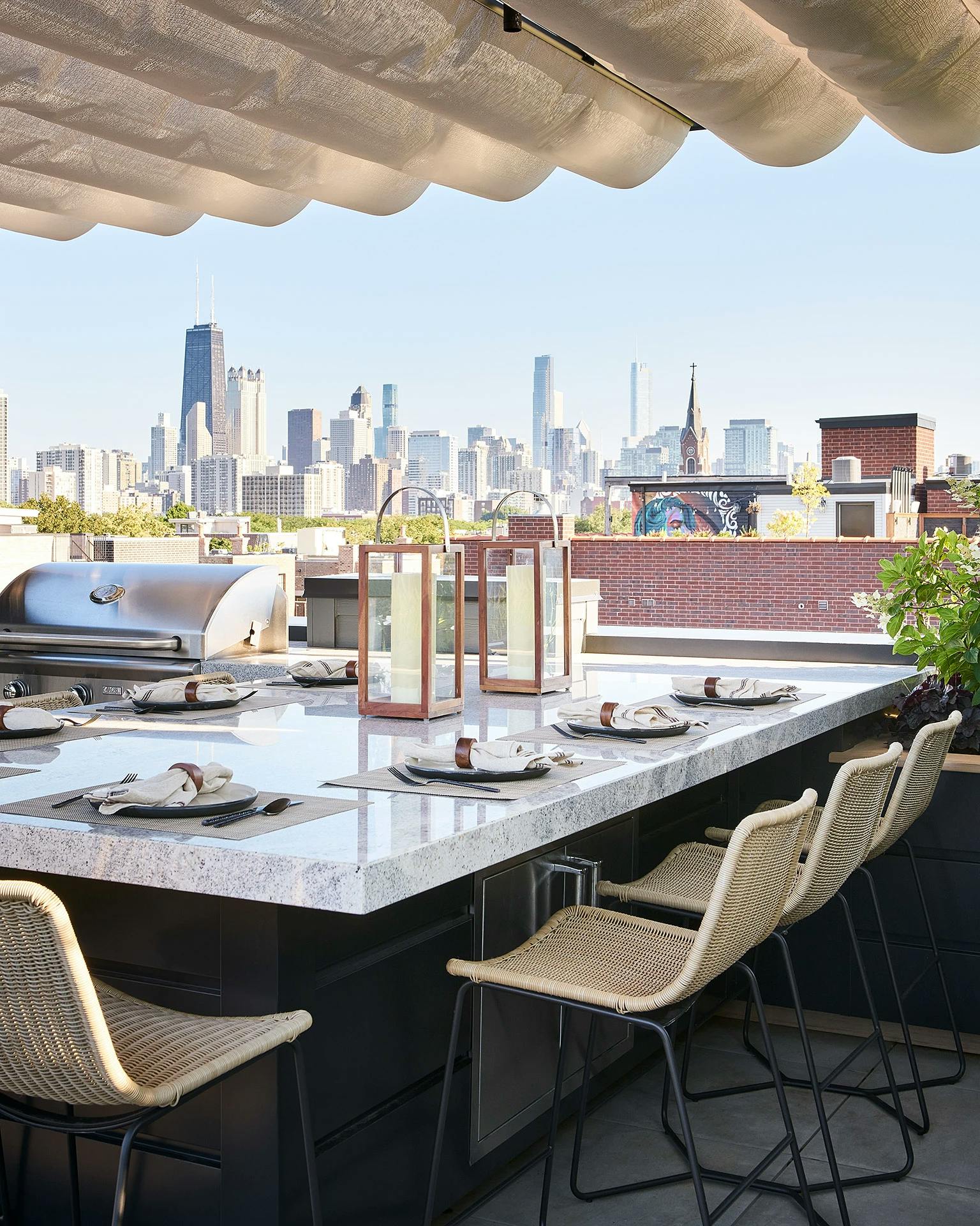 Roof deck with a large marble table and built in stainless steel grill overlooking the Chicago skyline in the distance.