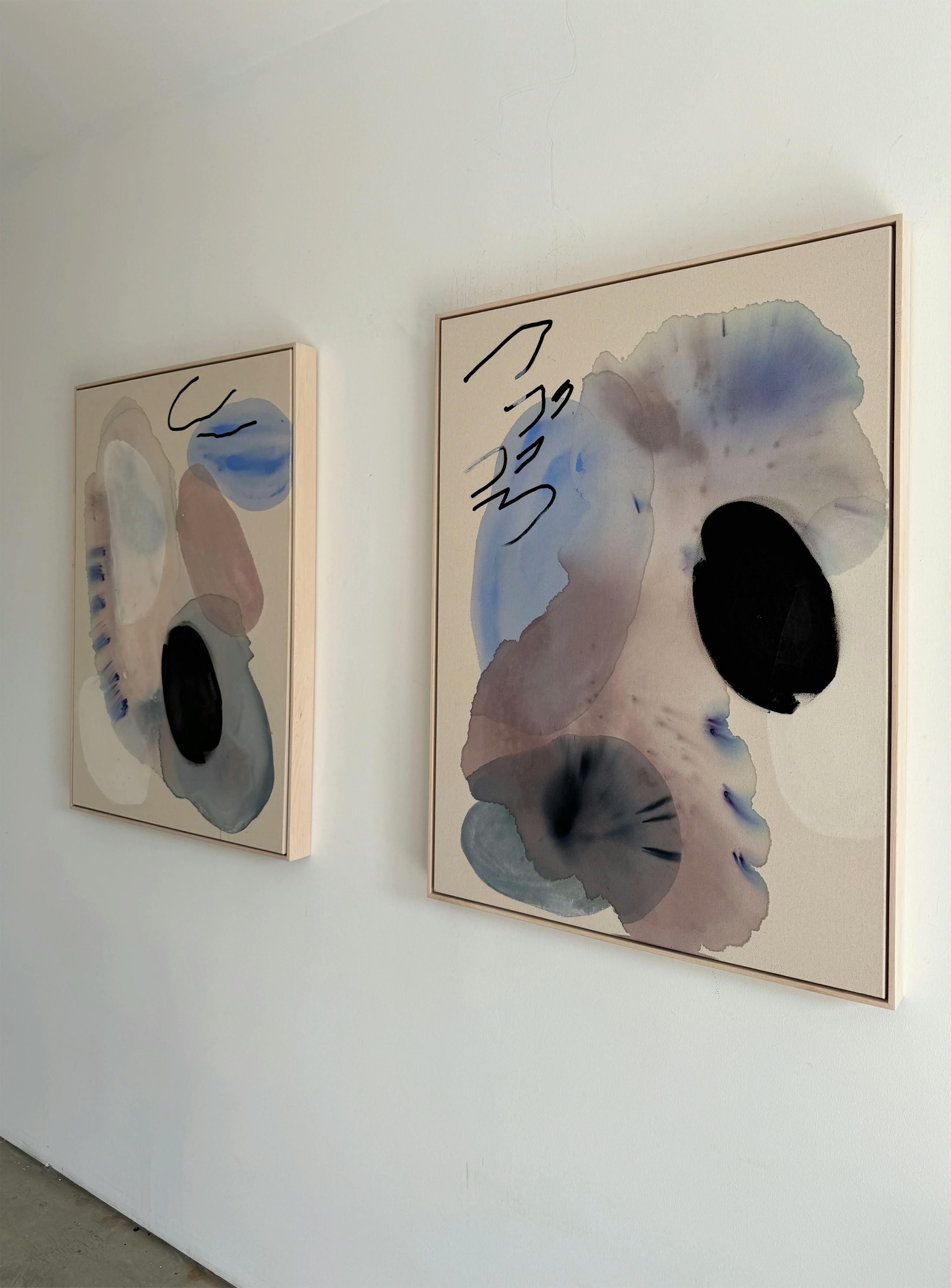 Two abstract, gestural paintings by artist Karina Bania installed side-by-side on a white wall in her studio.