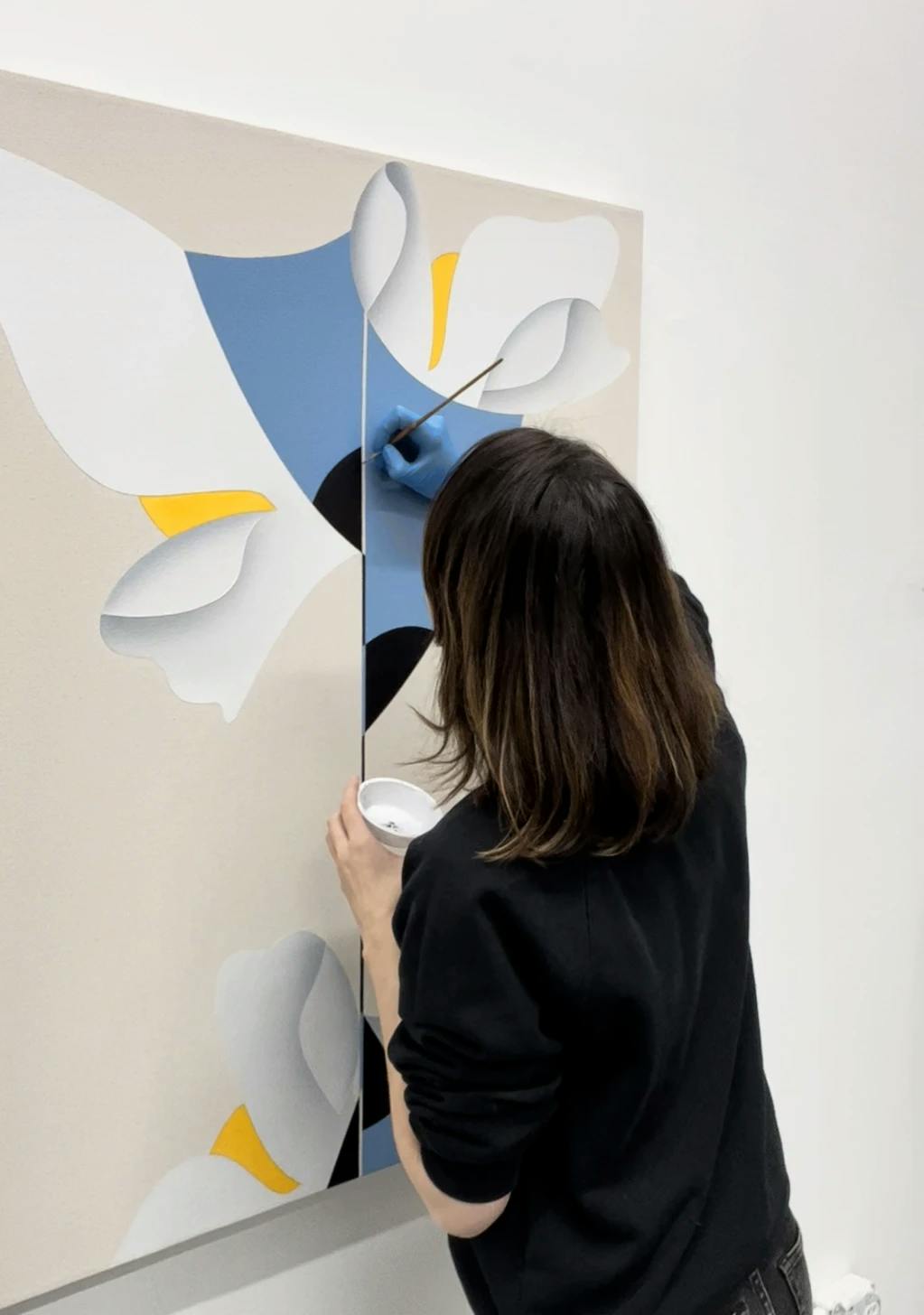Artist Senem Oezdogan working on a large blue, yellow and white painting in her studio. 