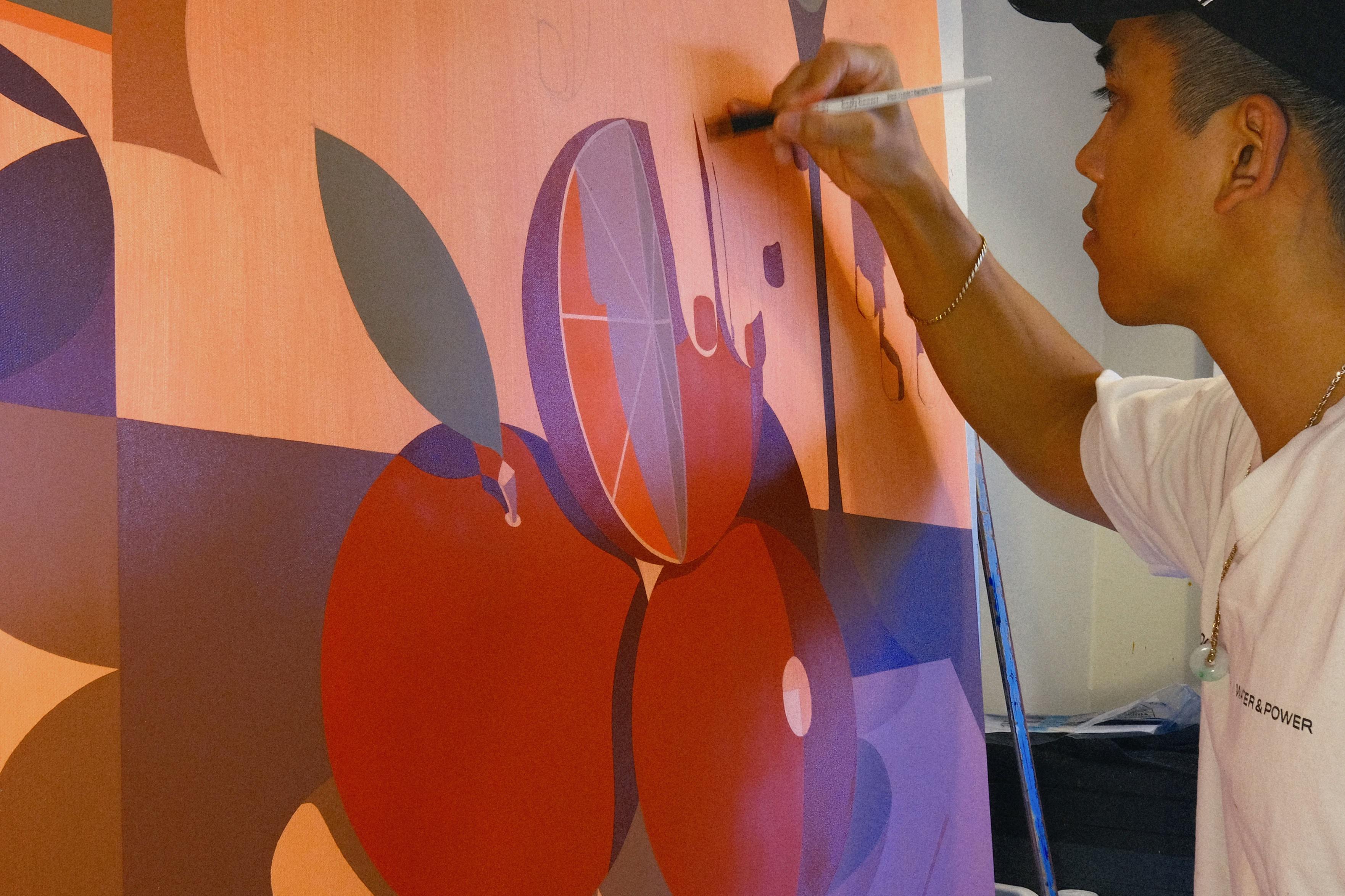 Artist Adrian Kay Wong working on a painting in his studio. 