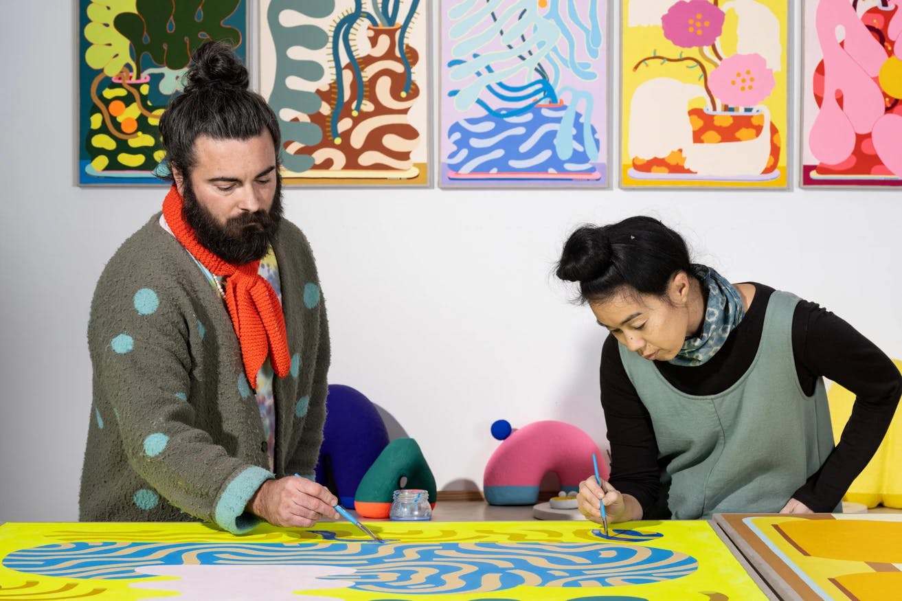 Artists Adam Frezza and Terri Chiao, also known as CHIAOZZA, working on a large-scale painting.