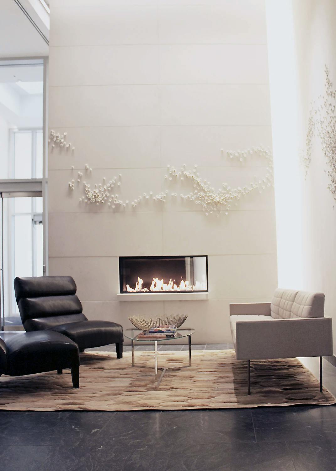 Custom porcelain wall installation by artist Christina Watka above a fireplace in the lounge area of a modern residential building.
