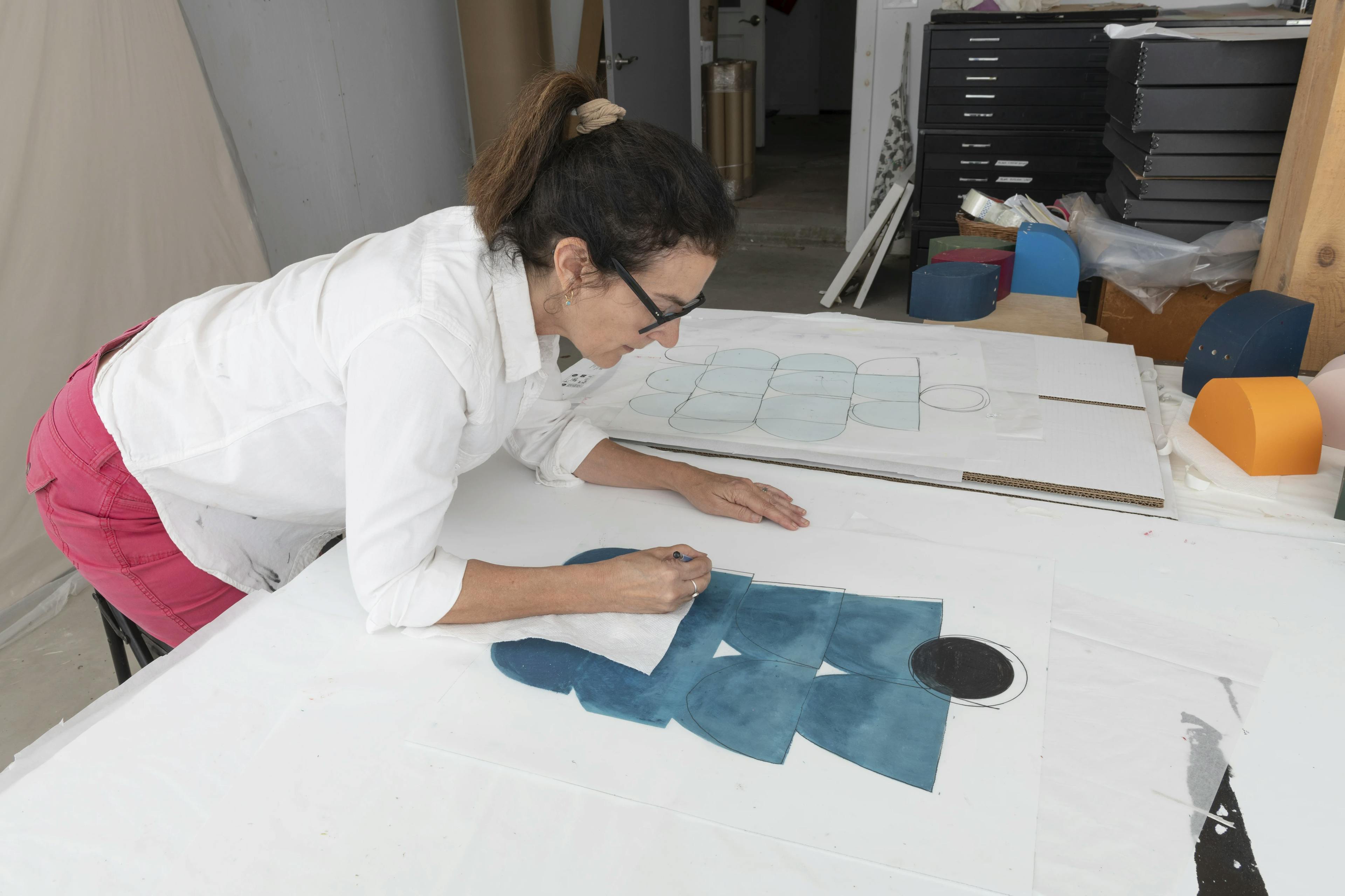 Vicki Sher using an oil pastel to create a teal, abstract drawing on drafting film.