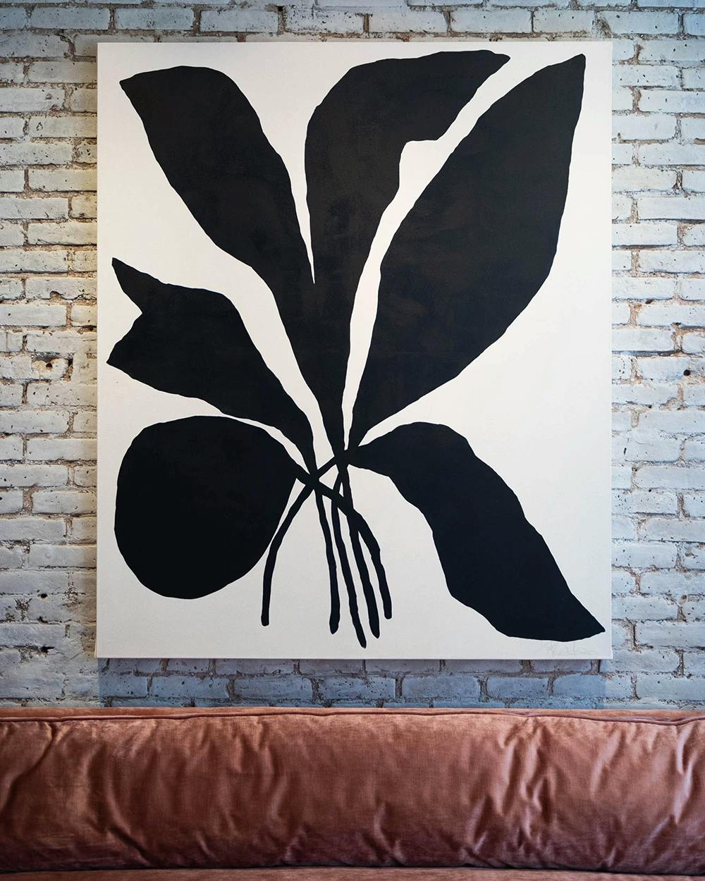 A large black and white botanical abstraction by artist Kate Roebuck on a white wall above a pink sofa at FIG.