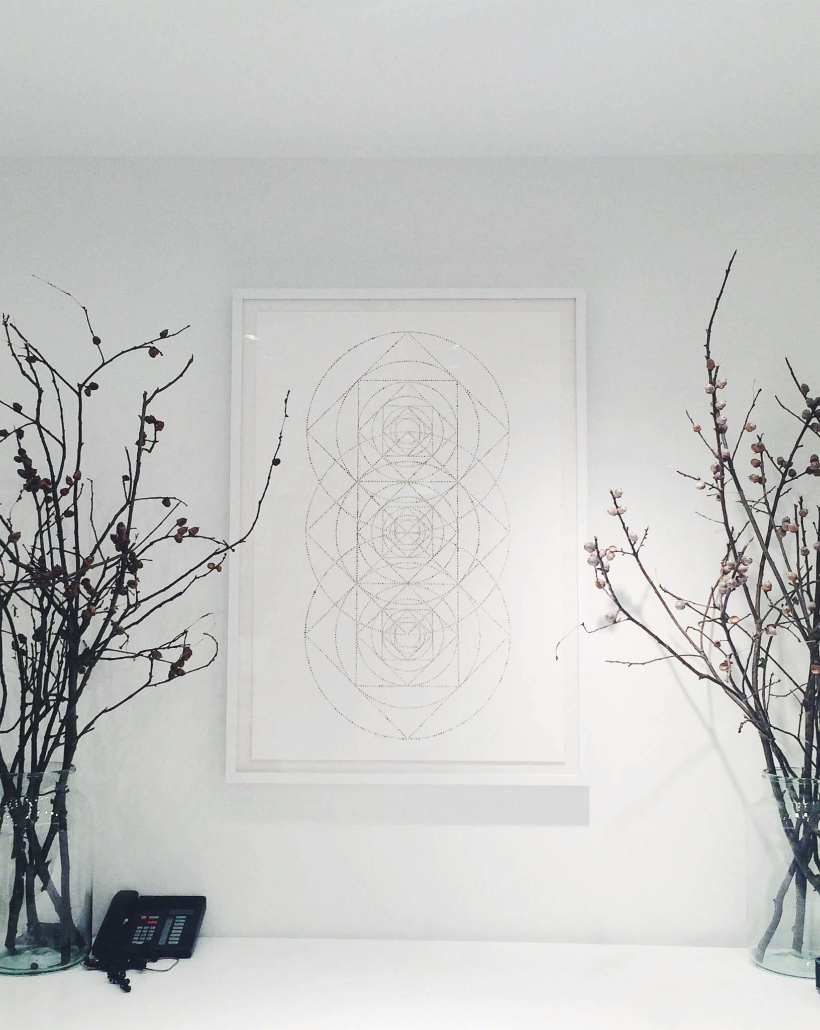 A framed artwork by artist Katrine Hildebrandt-Hussey of concentric circles on a white wall at Club Monaco.