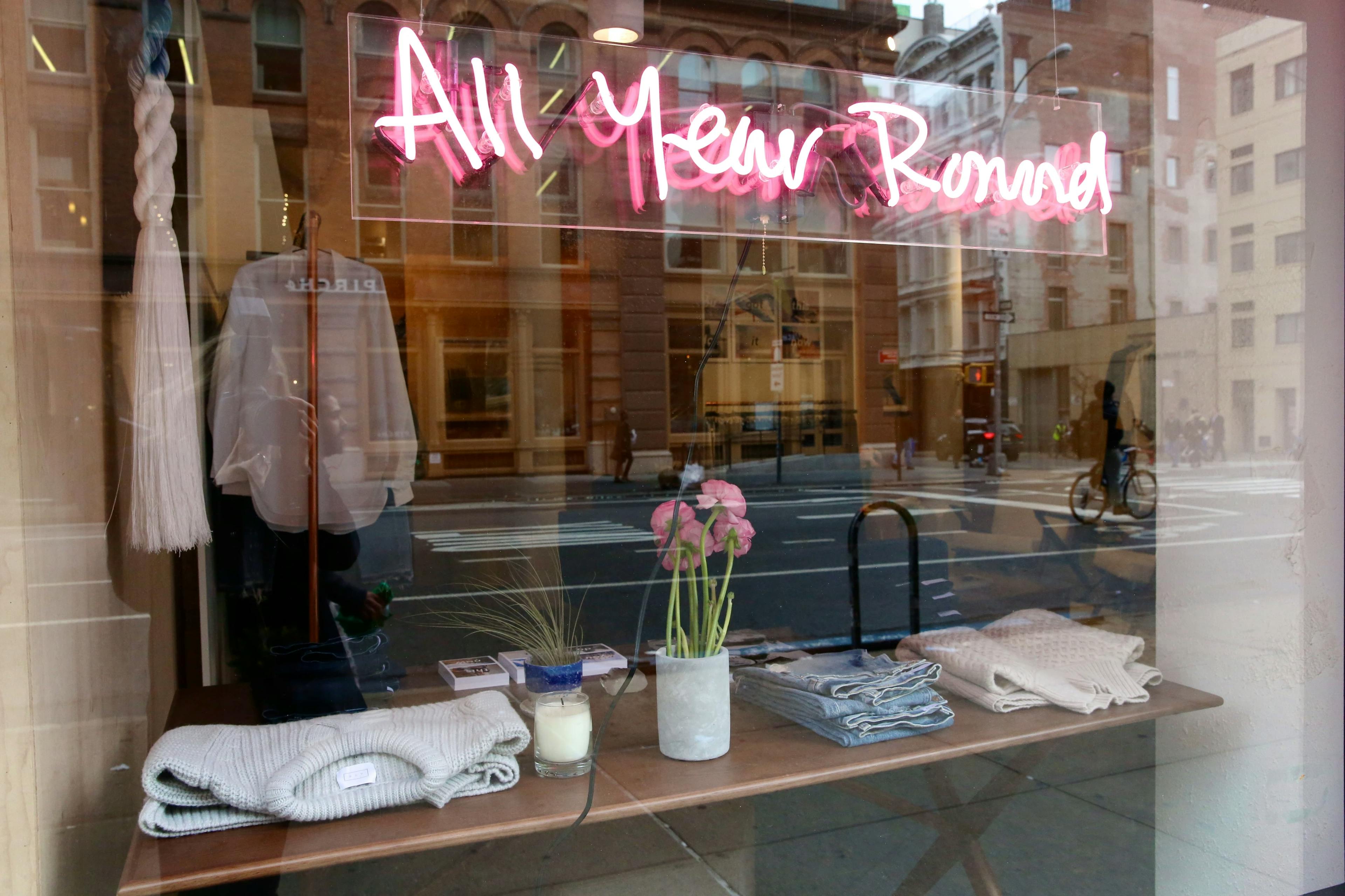 Glass storefront of AYR with a pink neon sign that says "All Year Round".