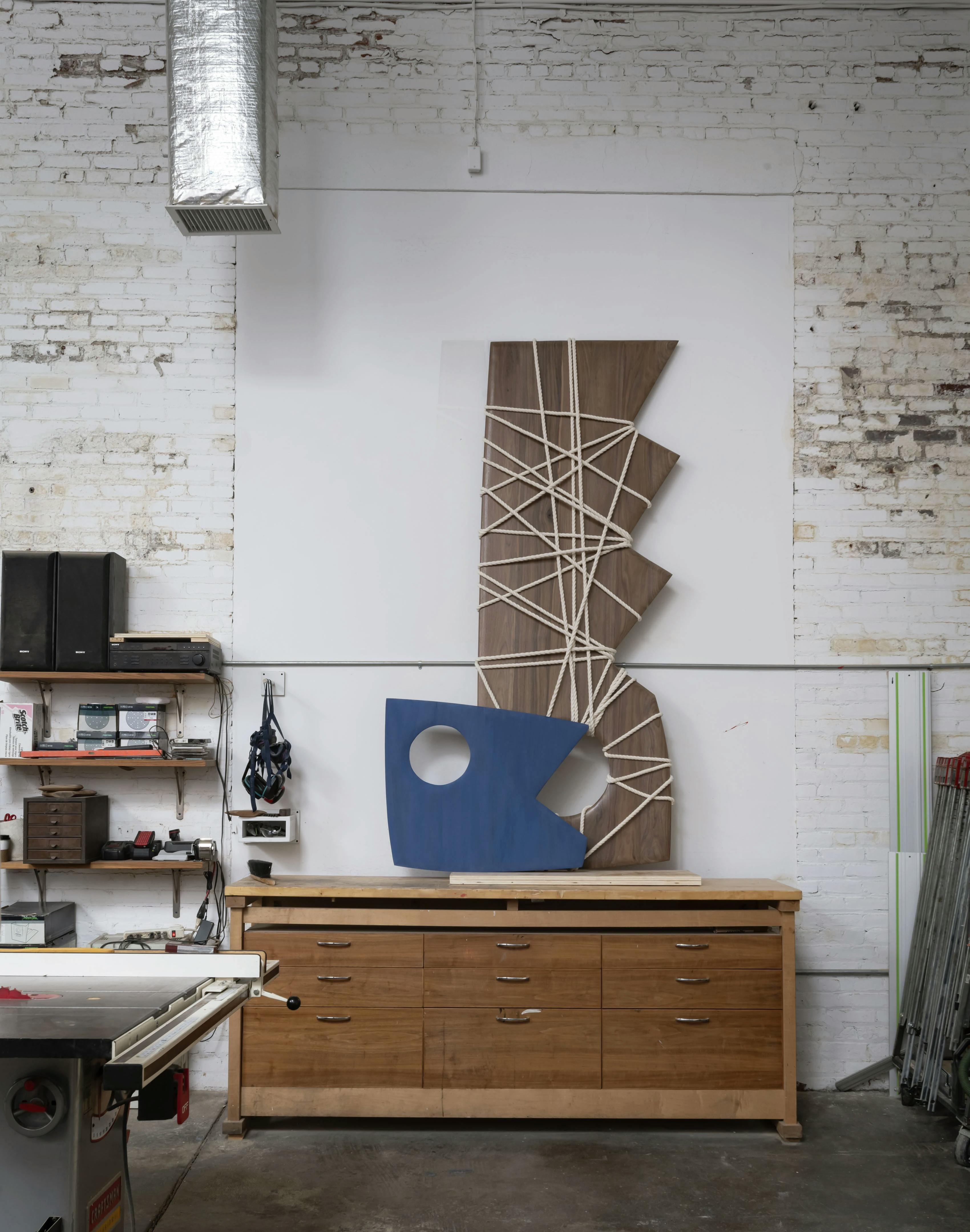 Two wall-based sculptures with jagged edges leaning against a white wall in artist Fitzhugh Karol's studio.