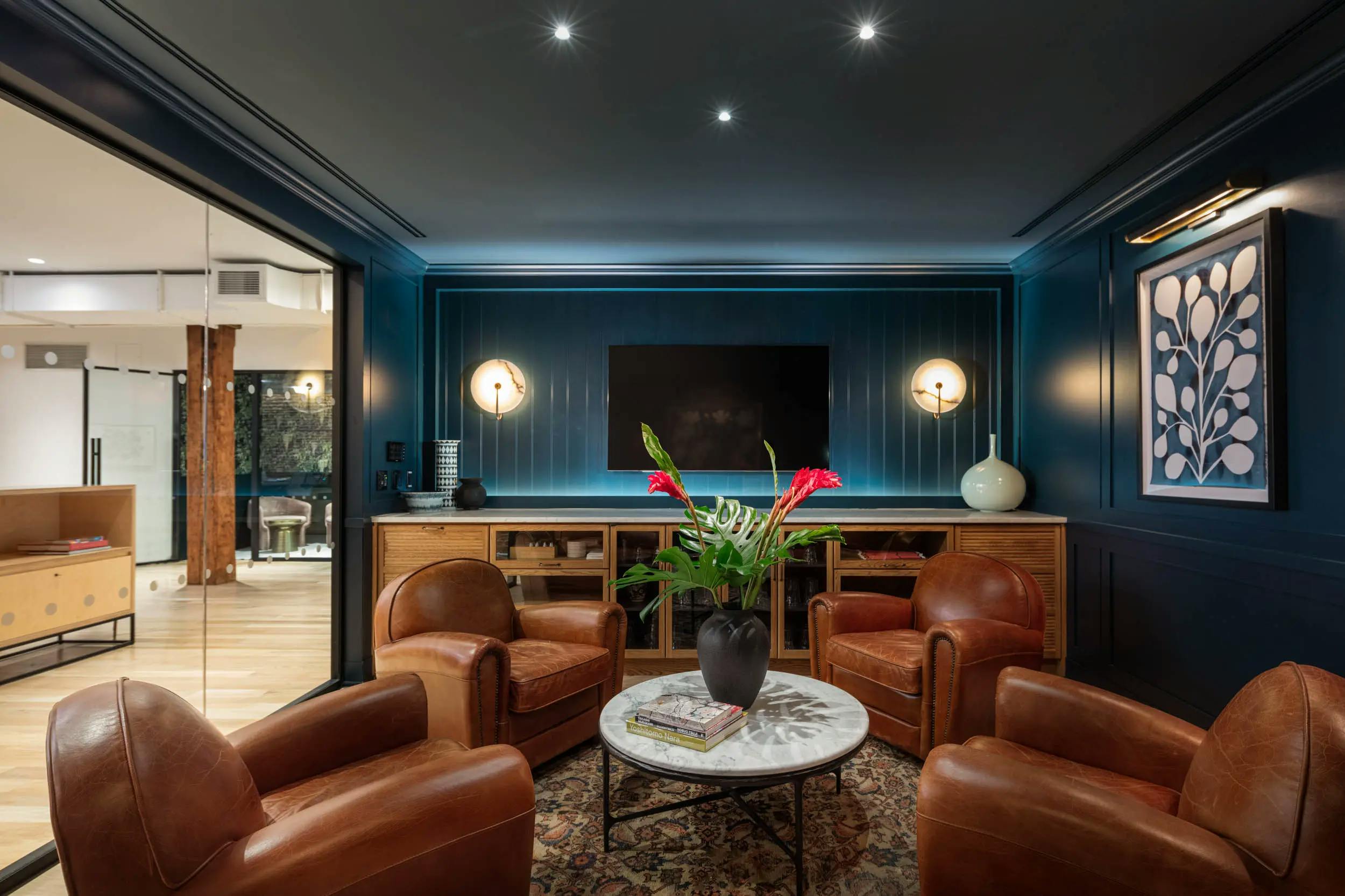 A blue conference room at FIG with four leather chairs and a blue botanical painting by Kate Roebuck installed on the right side of the room.