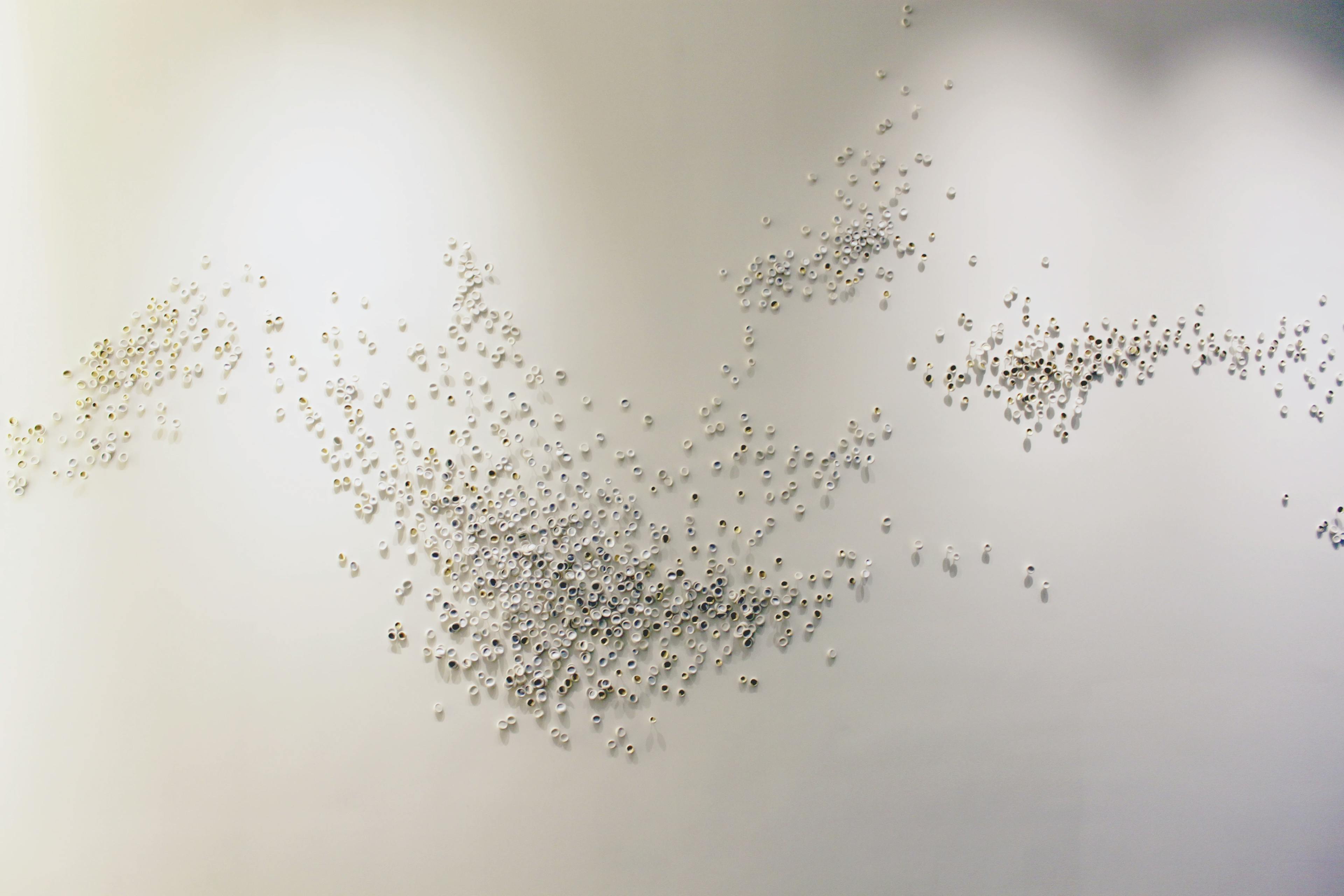 Porcelain wall installation made from small porcelain pieces by artist Christina Watka on a white wall.