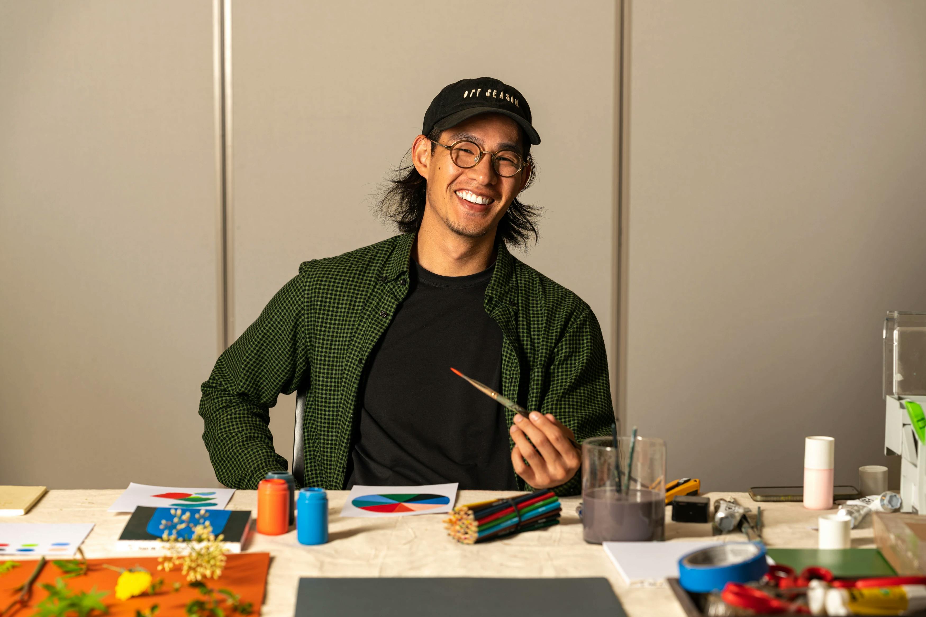 Artist Scott Sueme holding a paintbrush and smiling within his studio at MacArthur Place.
