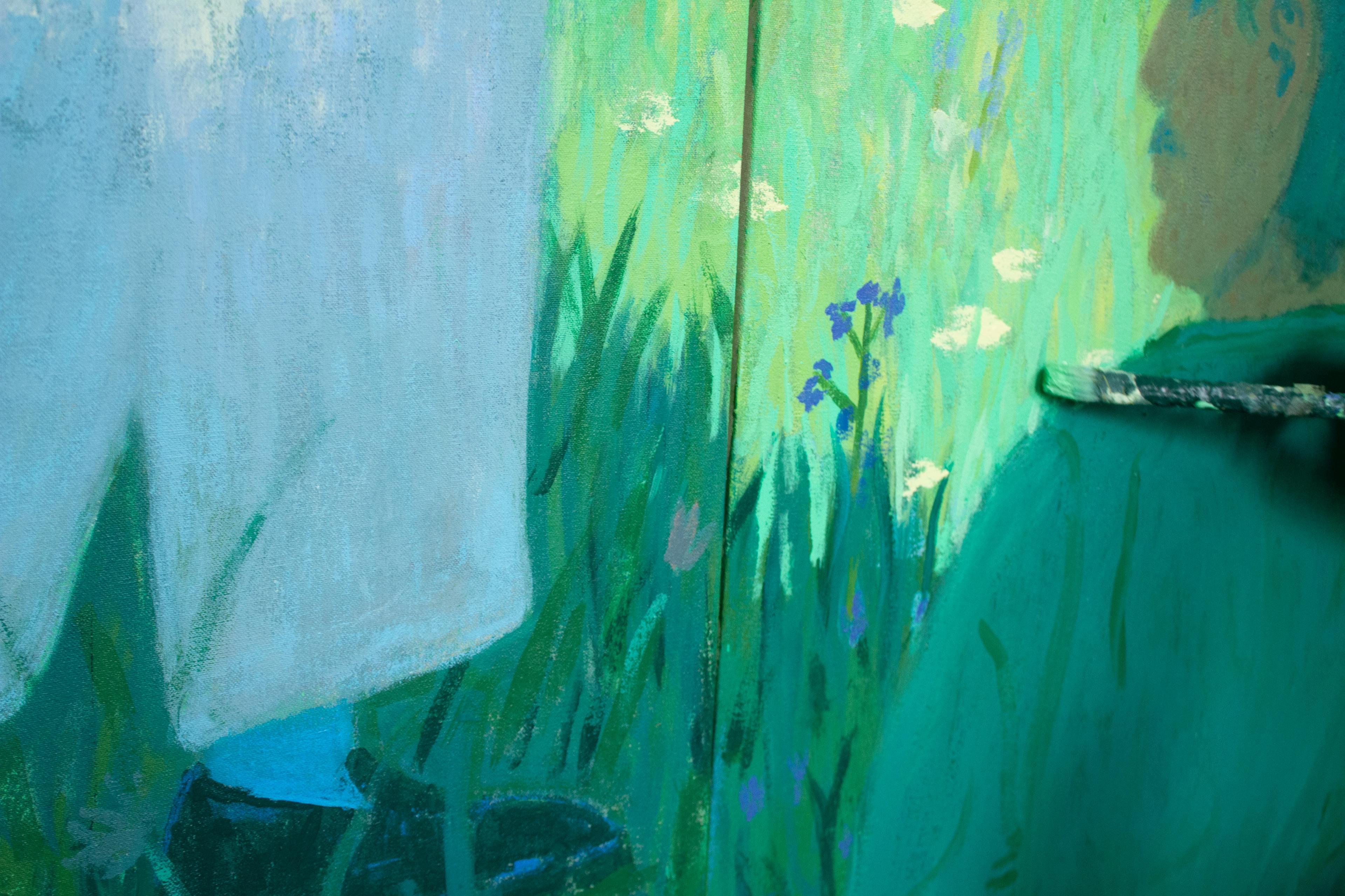 A close-up of artist Jackson Joyce painting figures in a grassy field.