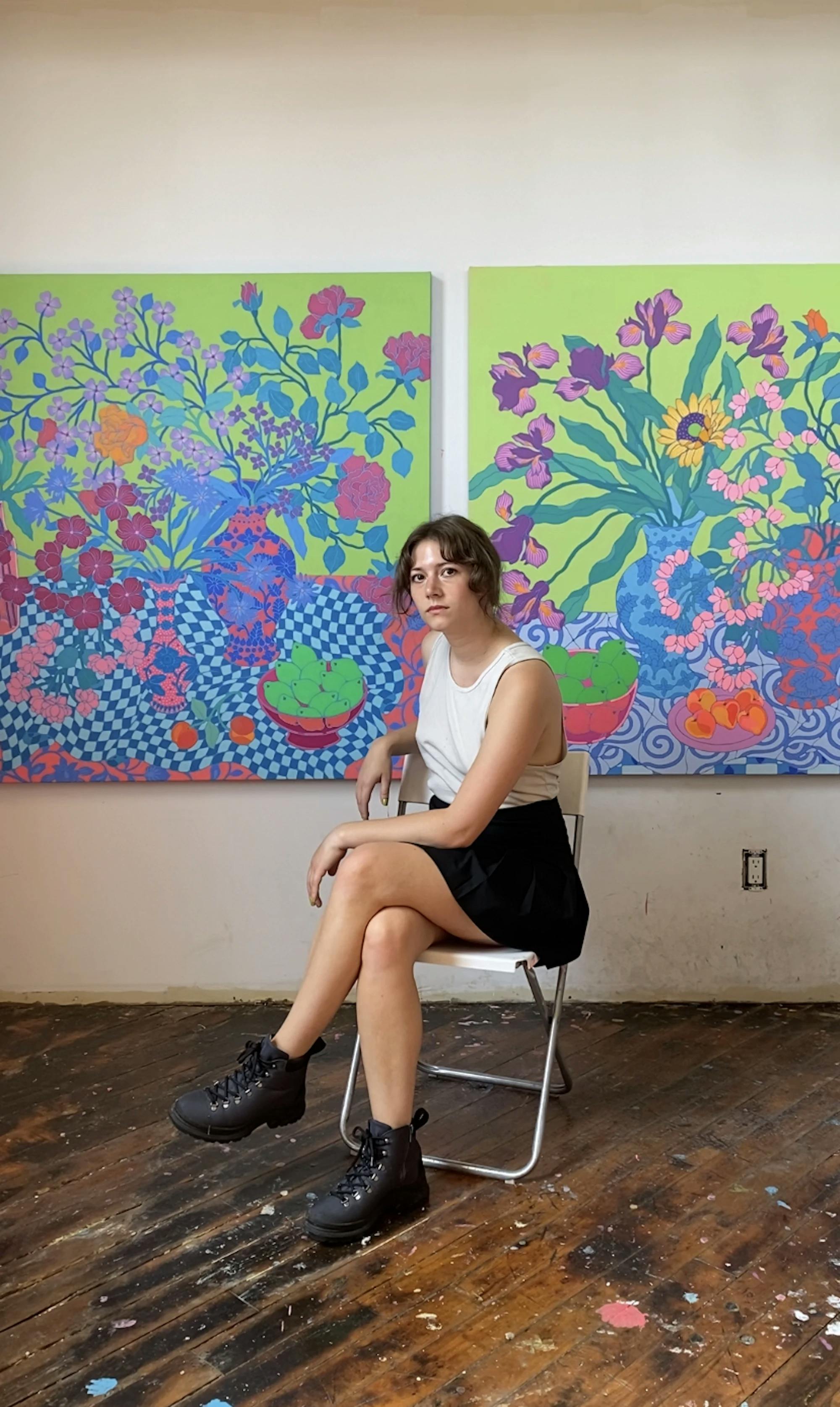 Artist Sarah Ingraham sitting in front of large floral paintings. 